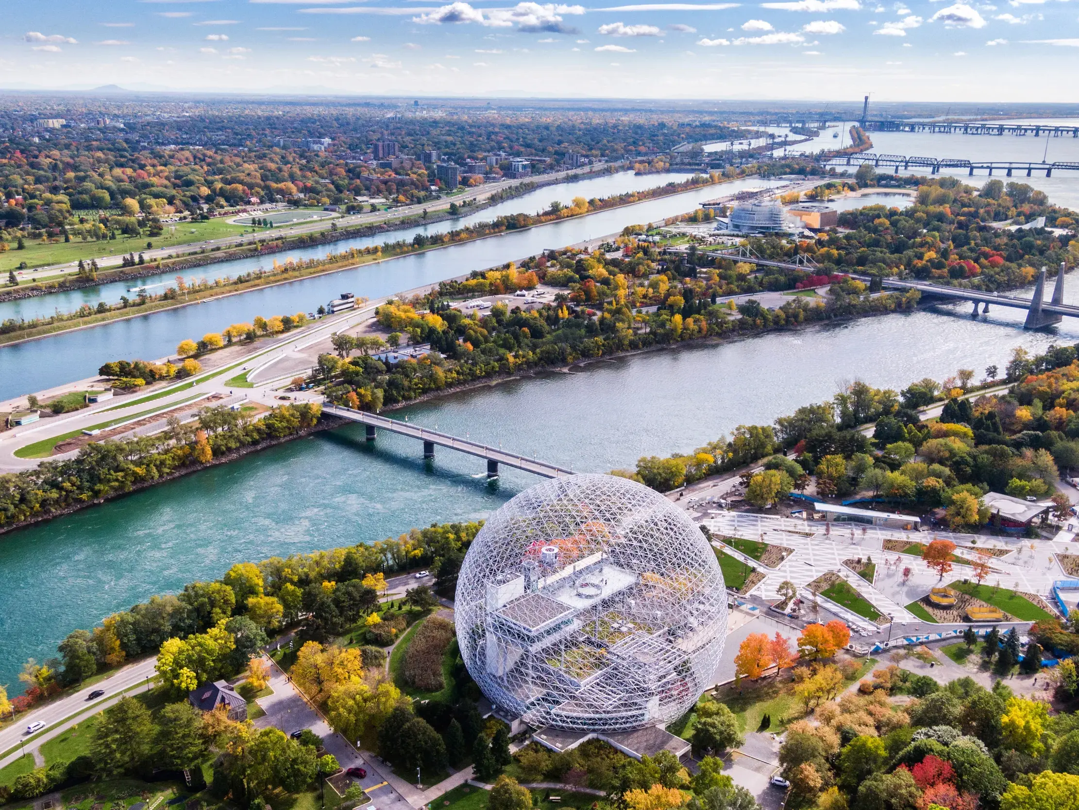 Vogelperspektive auf die Biosphäre in Montreal, umgeben vom Sankt-Lorenz-Strom mit buntem Herbstlaub am Ende der Radreise.