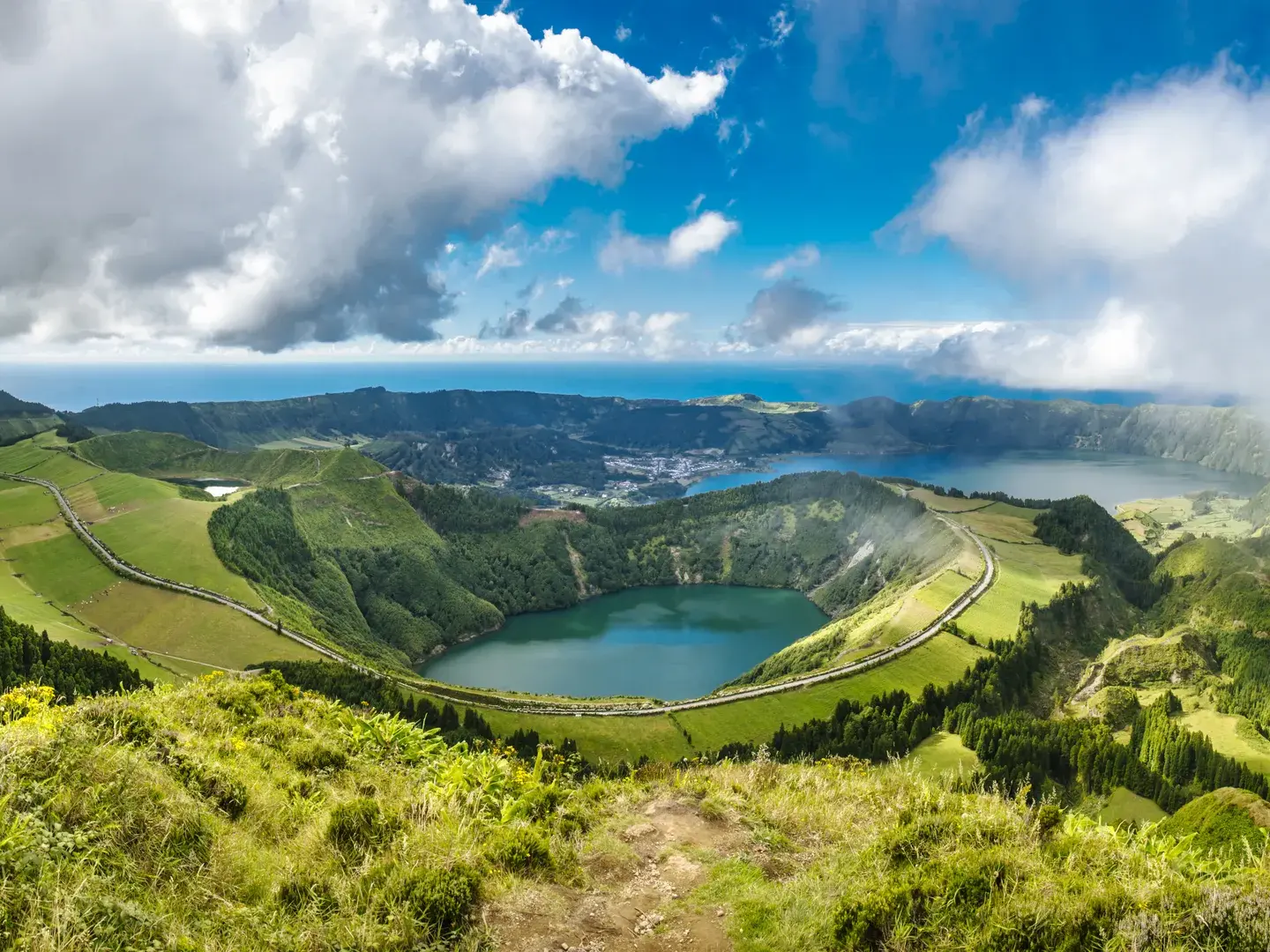 Weitblick von einem Wanderweg auf die grünen Kraterhänge und Seen der Caldeira de Sete Cidades auf der Azoreninsel São Miguel.