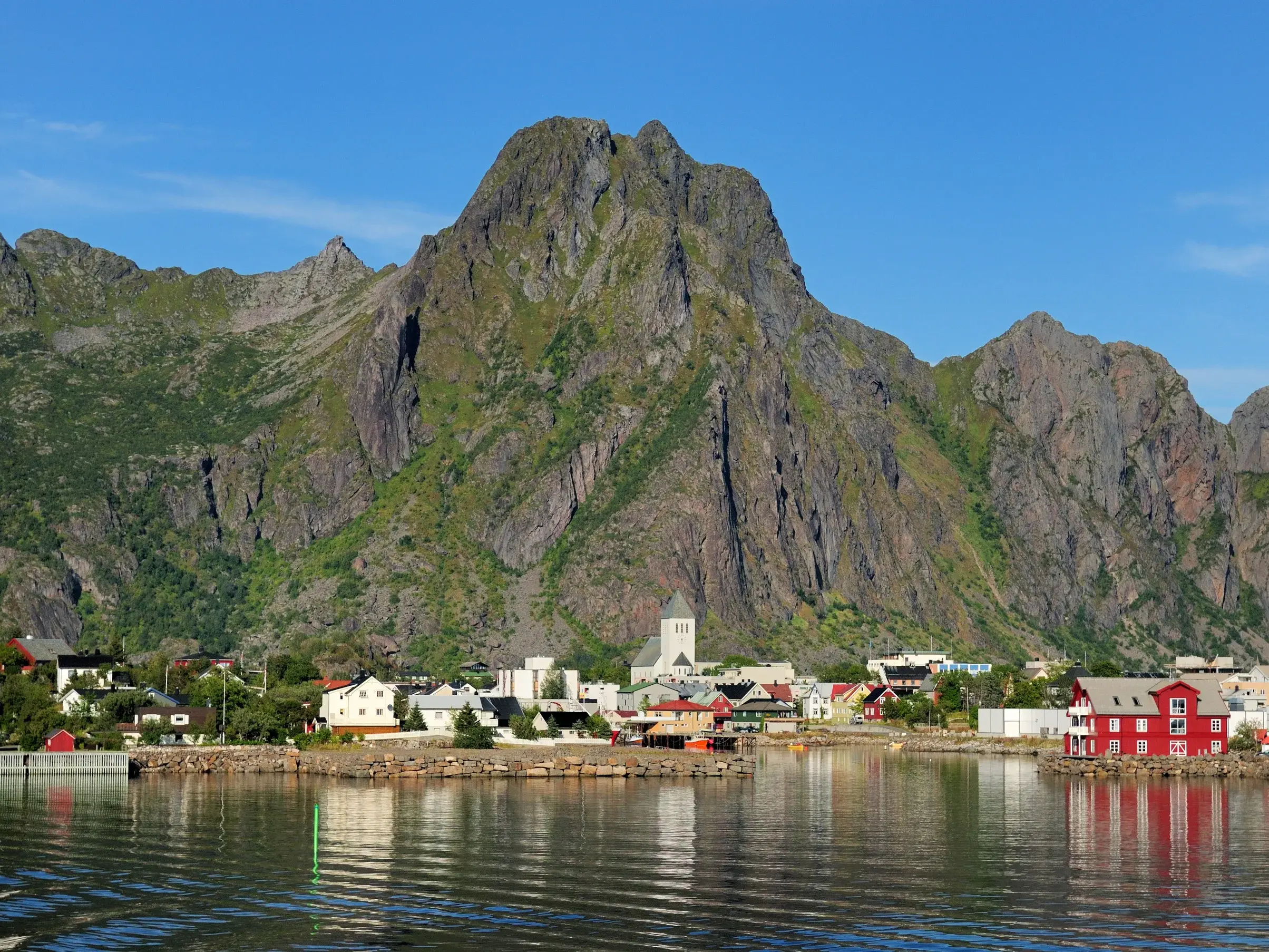 Farbenfrohe Holzhäuser des Fischerdorfs Kabelvåg am Fjord vor der imposanten Kulisse des Berges Vågakallen auf den Lofoten.