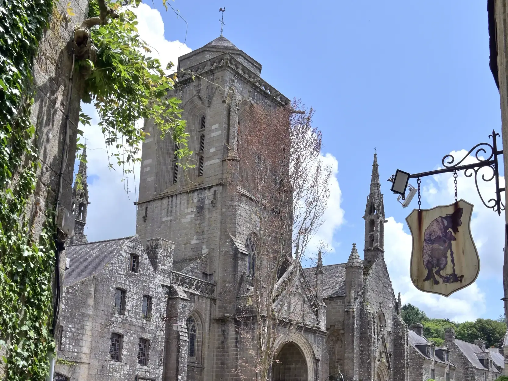Mittelalterliche Kirche in den romantischen Gassen von Locronan in der Bretagne bei strahlend blauem Himmel.
