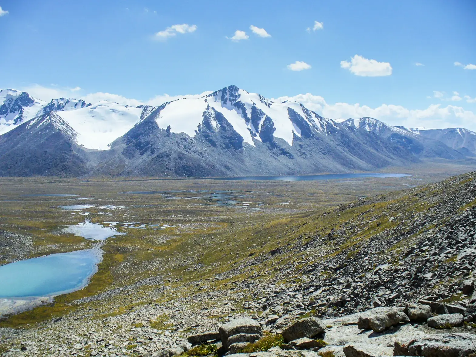 Panoramablick beim Trekking über das Uchemchek-Tal mit türkisen Bergseen auf die schneebedeckten Gipfel des Terskej-Alatau.