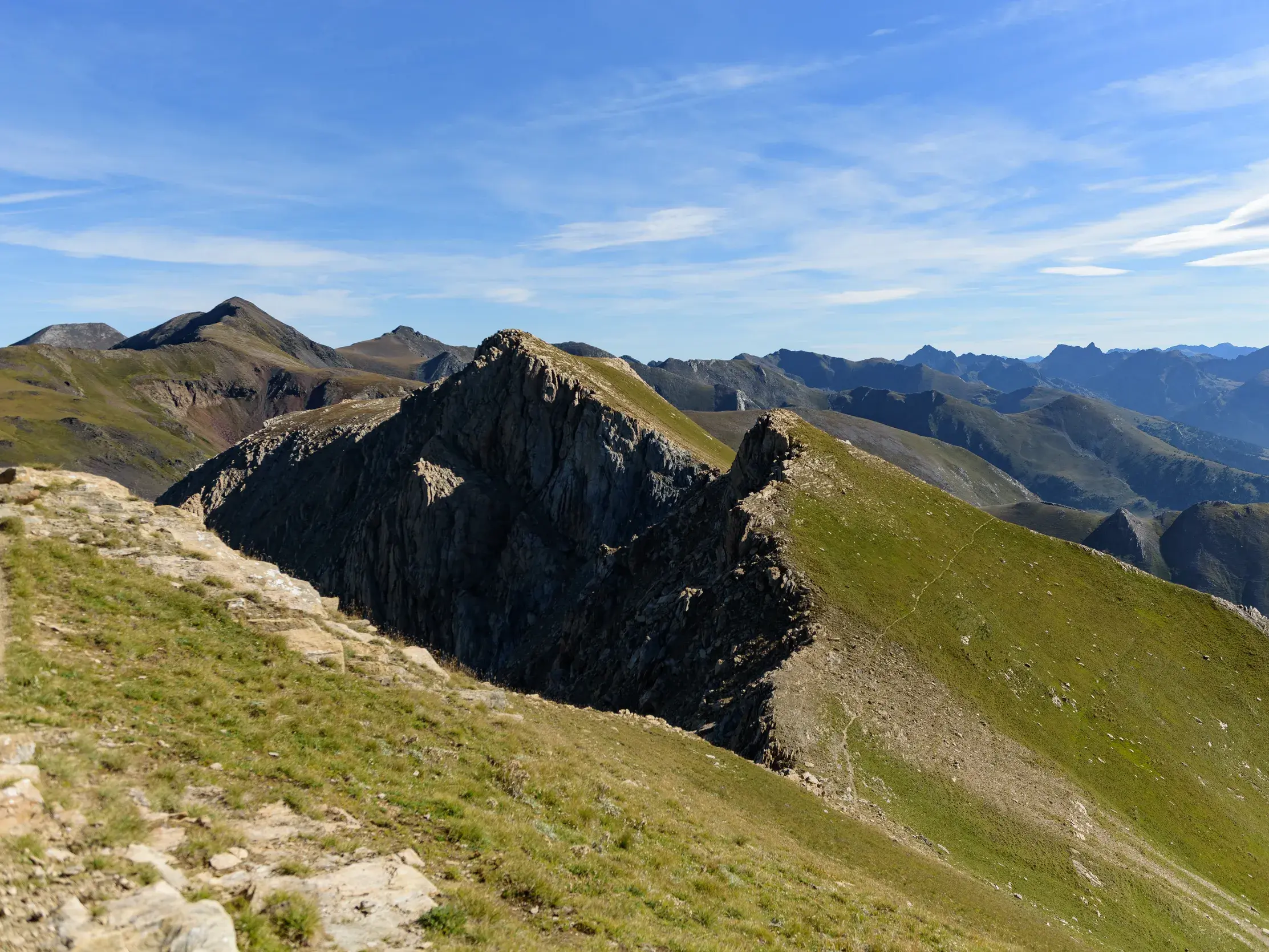 Gratwanderung zum Pic de la Serrera in Andorra mit Panoramablick über die weite Berglandschaft der Pyrenäen bei Sonnenschein.