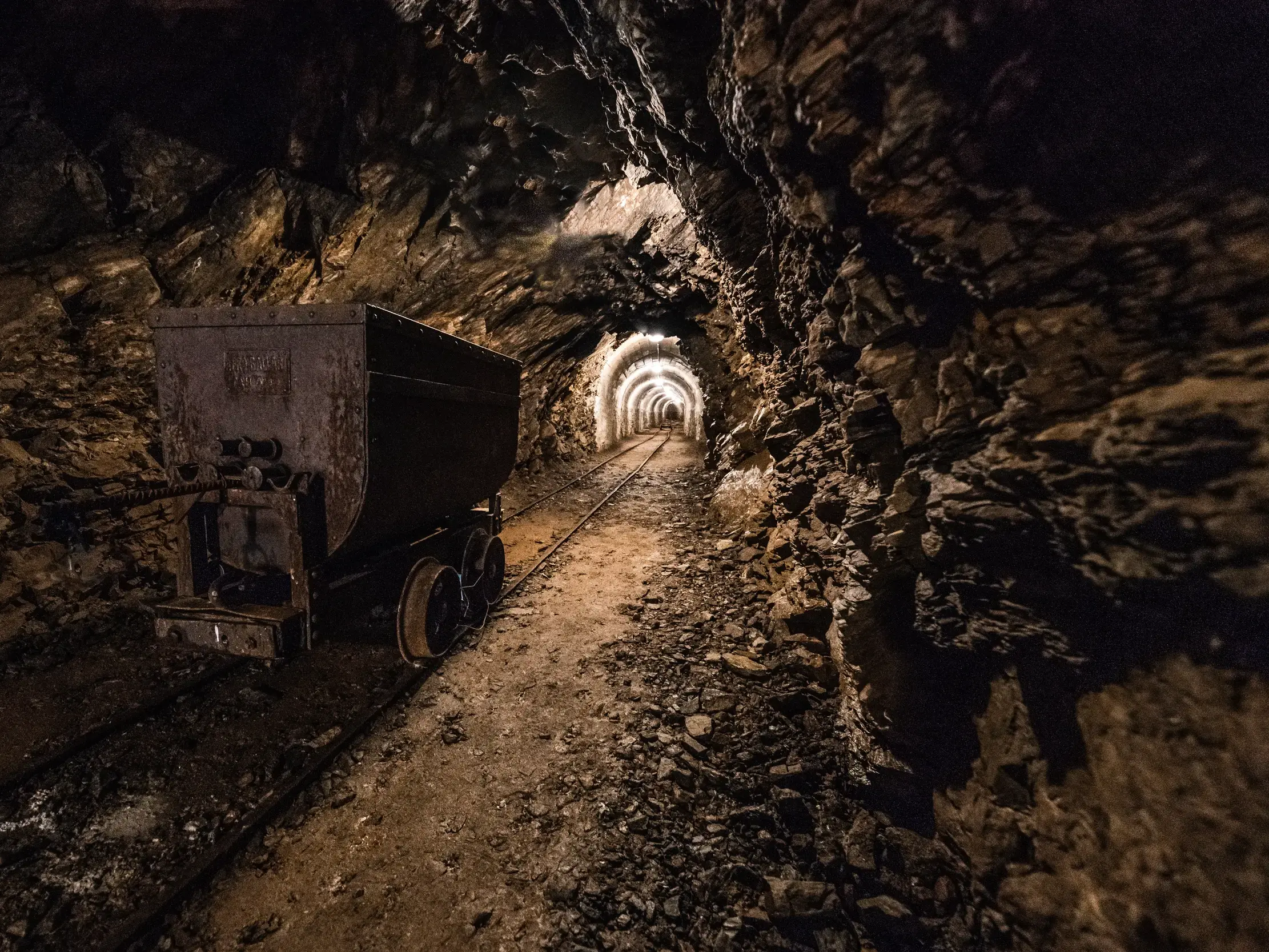 Ein alter Lorenwagen steht auf Schienen im felsigen Karlsstollen des ehemaligen Silberbergwerks am Schneeberg.