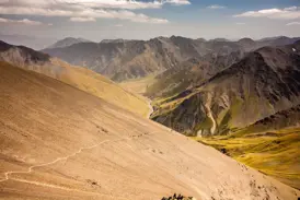 Eine Trekking-Gruppe wandert auf einem schmalen Pfad über eine steile Geröllhalde zum Atsunta-Pass im georgischen Kaukasus.