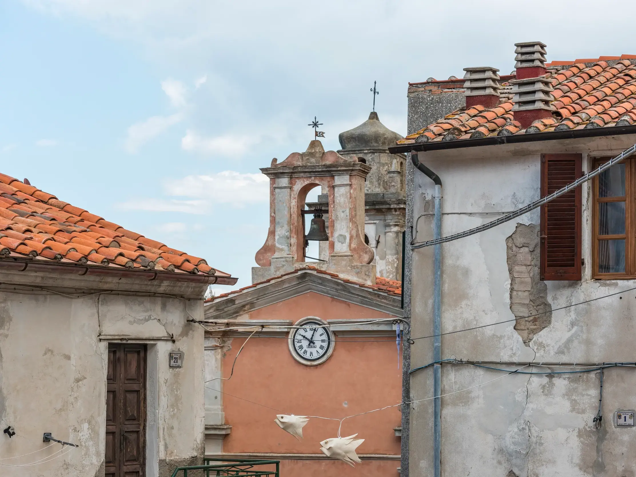 Verwinkelte Gasse im Bergdorf Poggio auf Elba mit Blick auf den Kirchturm und alte Häuser mit Terrakottadächern.