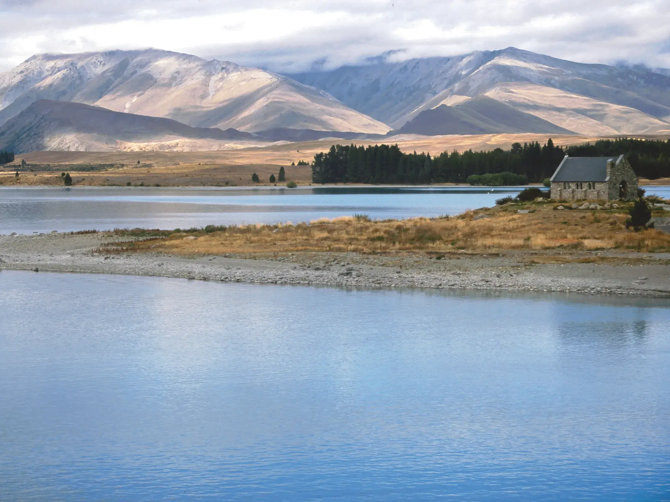 Die Kirche des guten Hirten steht am Ufer des blauen Tekapo Sees in Neuseeland vor der Bergkulisse der Südalpen.
