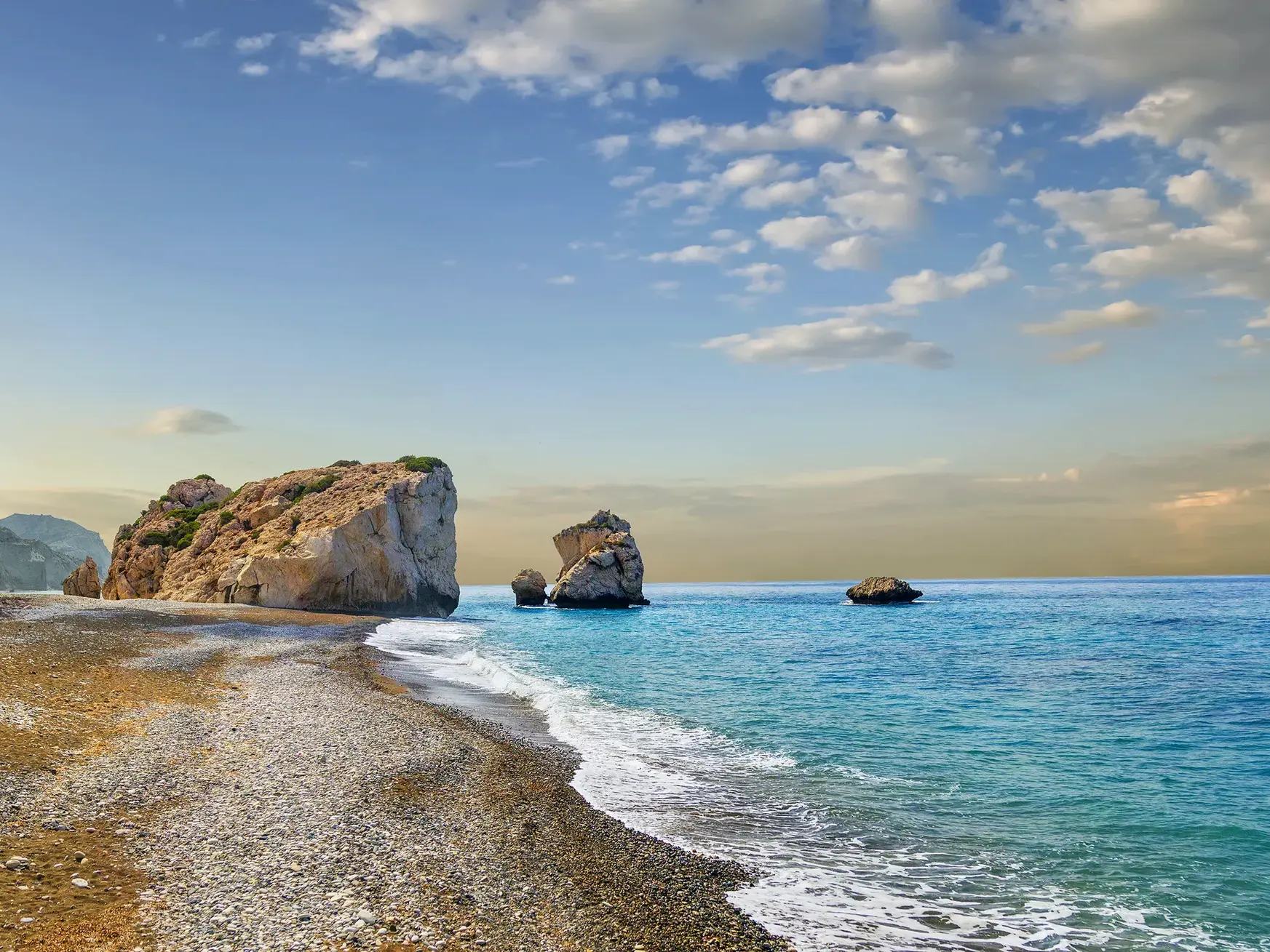 Der sagenumwobene Felsen der Aphrodite ragt bei Paphos aus dem Meer, die Wellen umspülen den Kieselstrand Zyperns.
