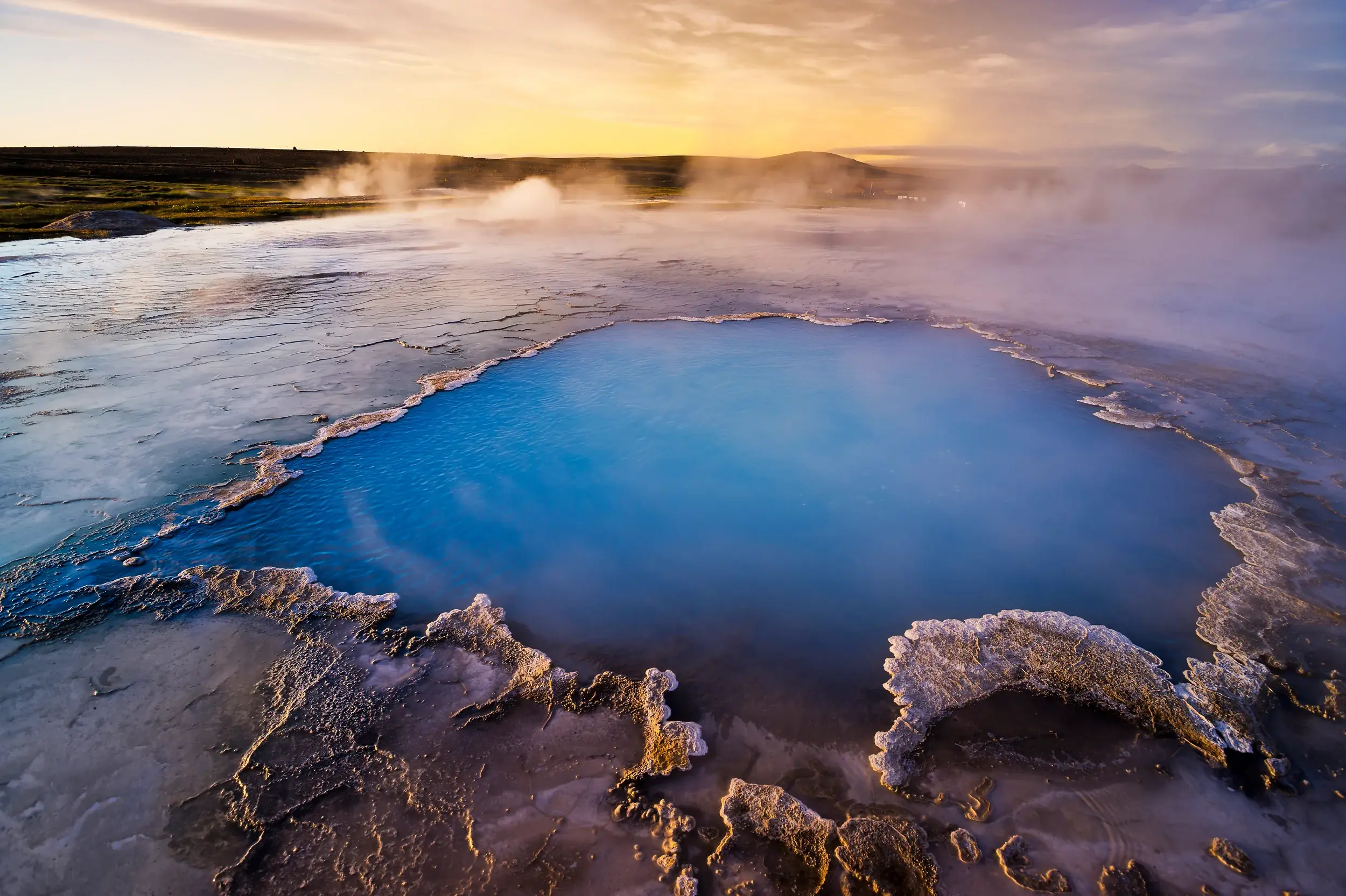 Eine leuchtend blaue heiße Quelle dampft in der archaischen Landschaft des Geothermalgebiets Hveravellir im Hochland von Island.