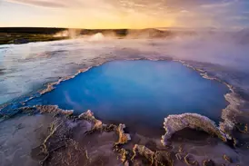 Eine leuchtend blaue heiße Quelle dampft in der archaischen Landschaft des Geothermalgebiets Hveravellir im Hochland von Island.