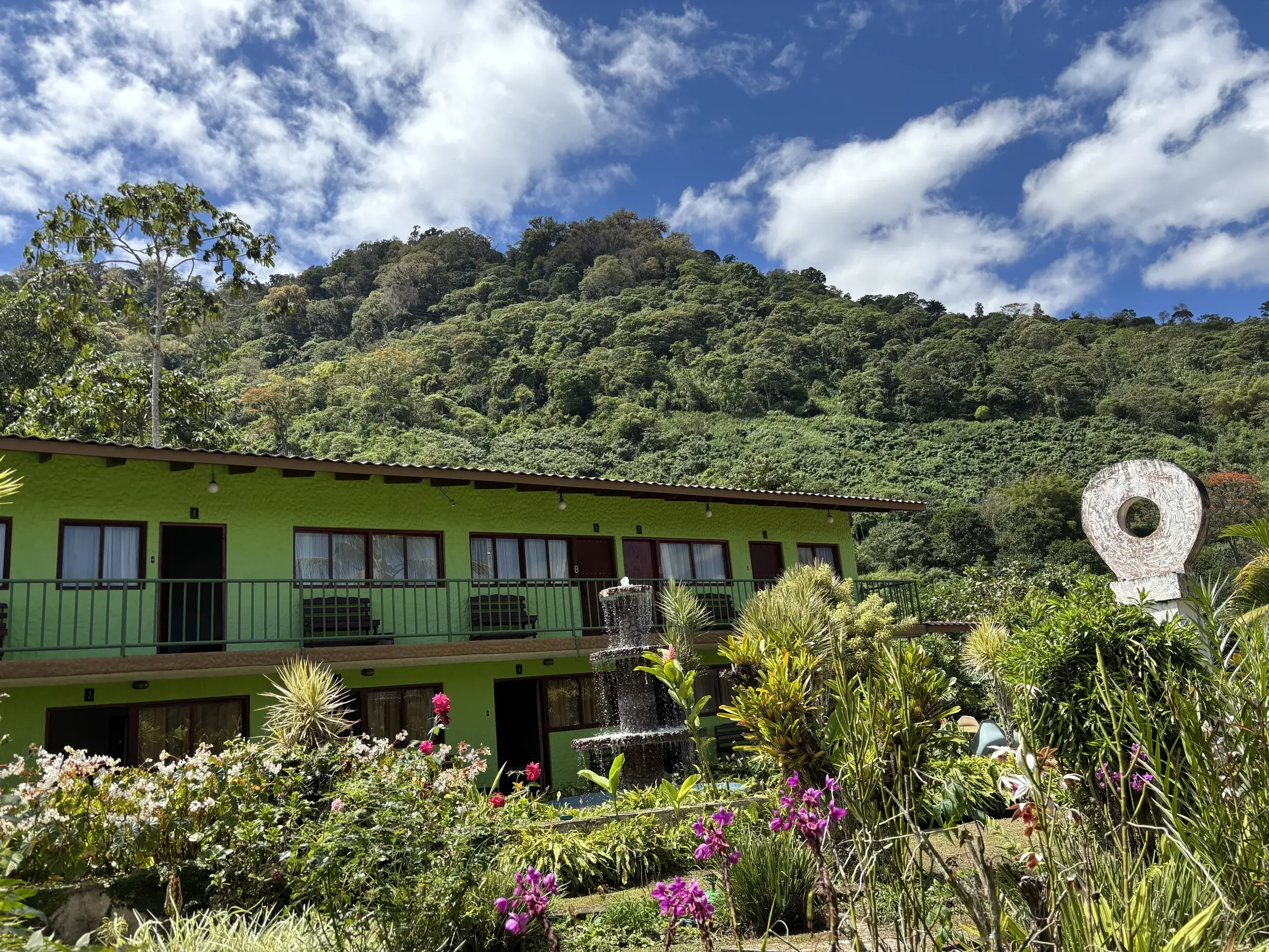 Das Hotel Boquete Garden Inn in Panama, eingebettet in einen blühenden Garten vor der grünen Berglandschaft von Boquete.