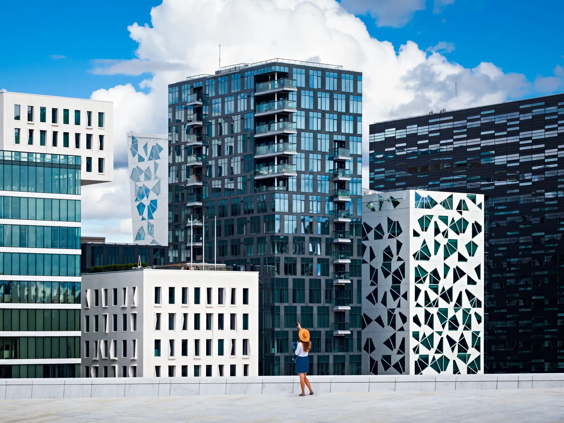 Eine Frau steht auf einem Dach in Oslo und blickt auf die modernen Hochhäuser des Barcode-Projekts im Viertel Björvika.