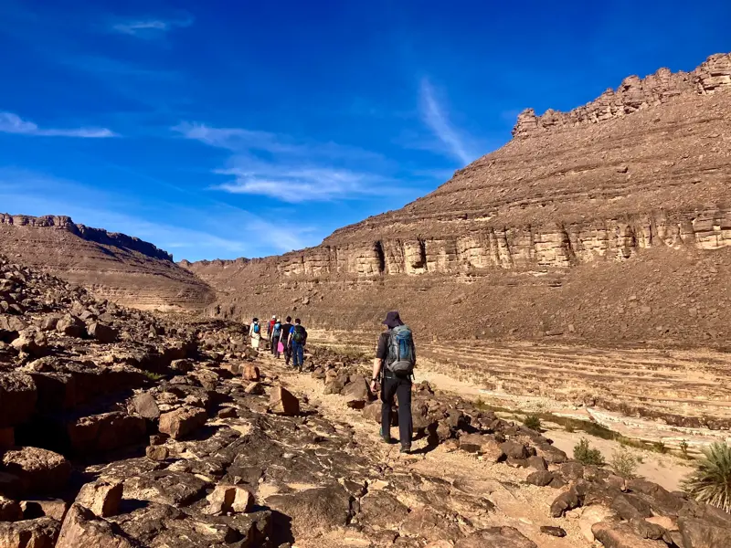 Eine Hauser-Wandergruppe beim Trekking auf einem Pfad durch eine Felsschlucht im Tassili n'Ajjer Nationalpark, Algerien.