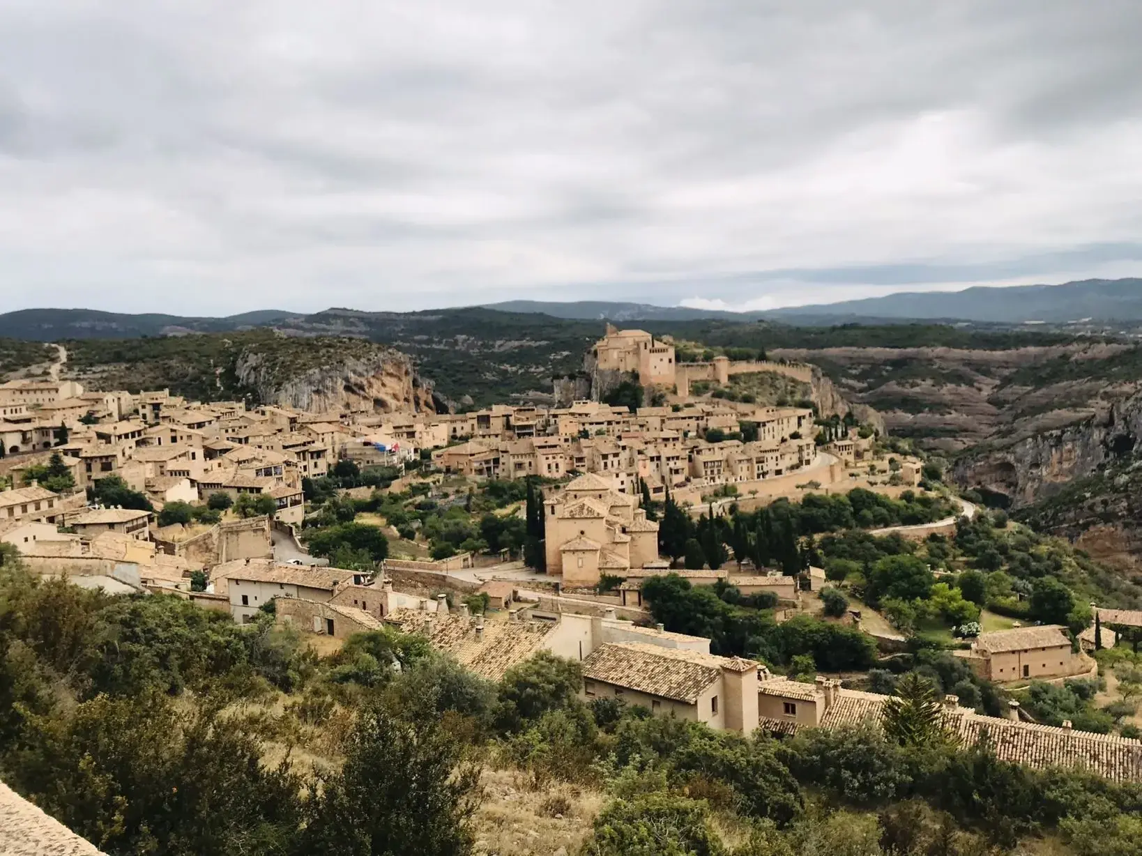 Weitblick auf das mittelalterliche Dorf Alquézar, eingebettet in die grüne Canyonlandschaft der Sierra de Guara in Aragonien.