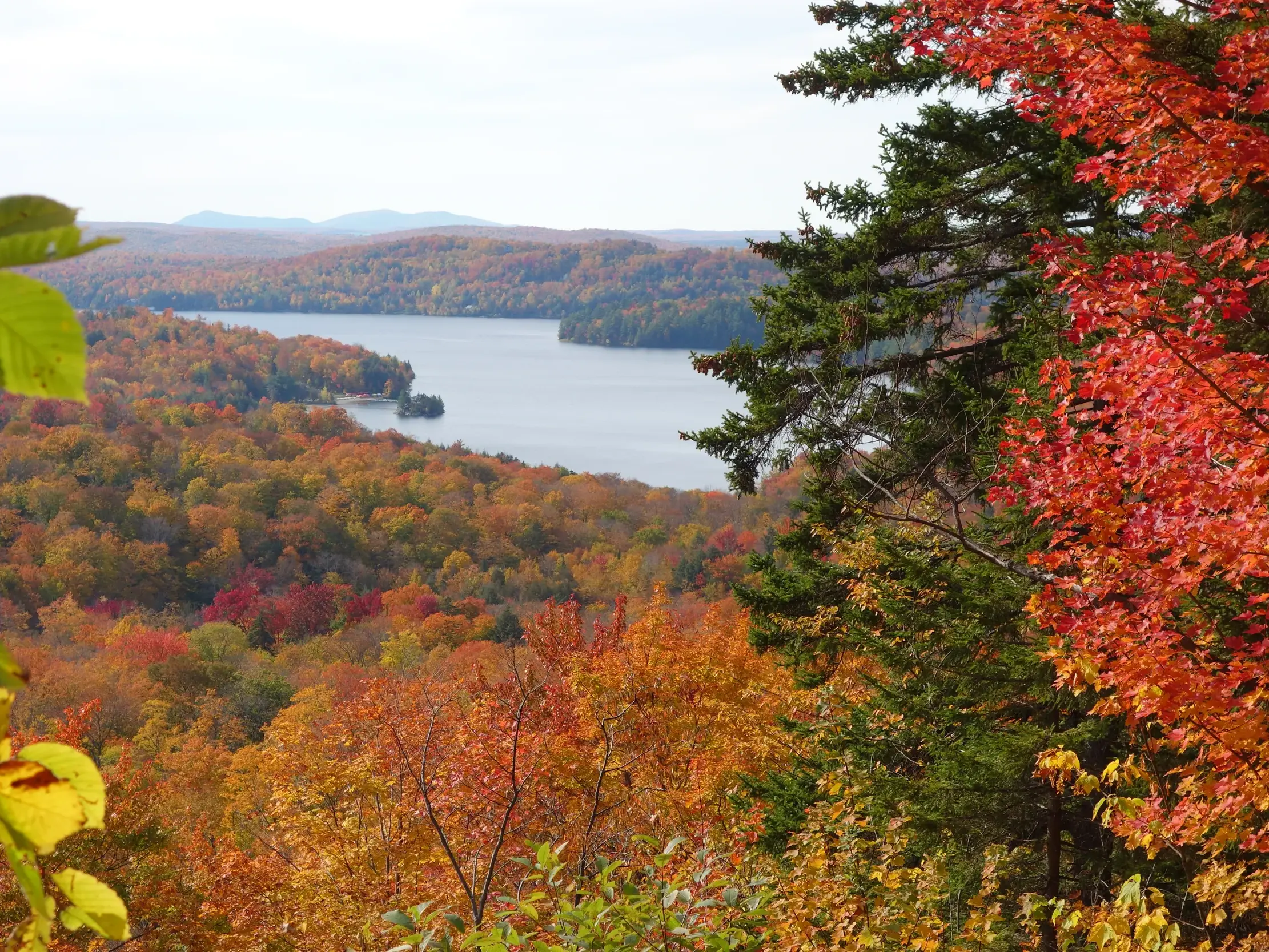 Weitblick beim Wandern in Québec über einen See und die farbenprächtigen Wälder des Indian Summer in Ostkanada.