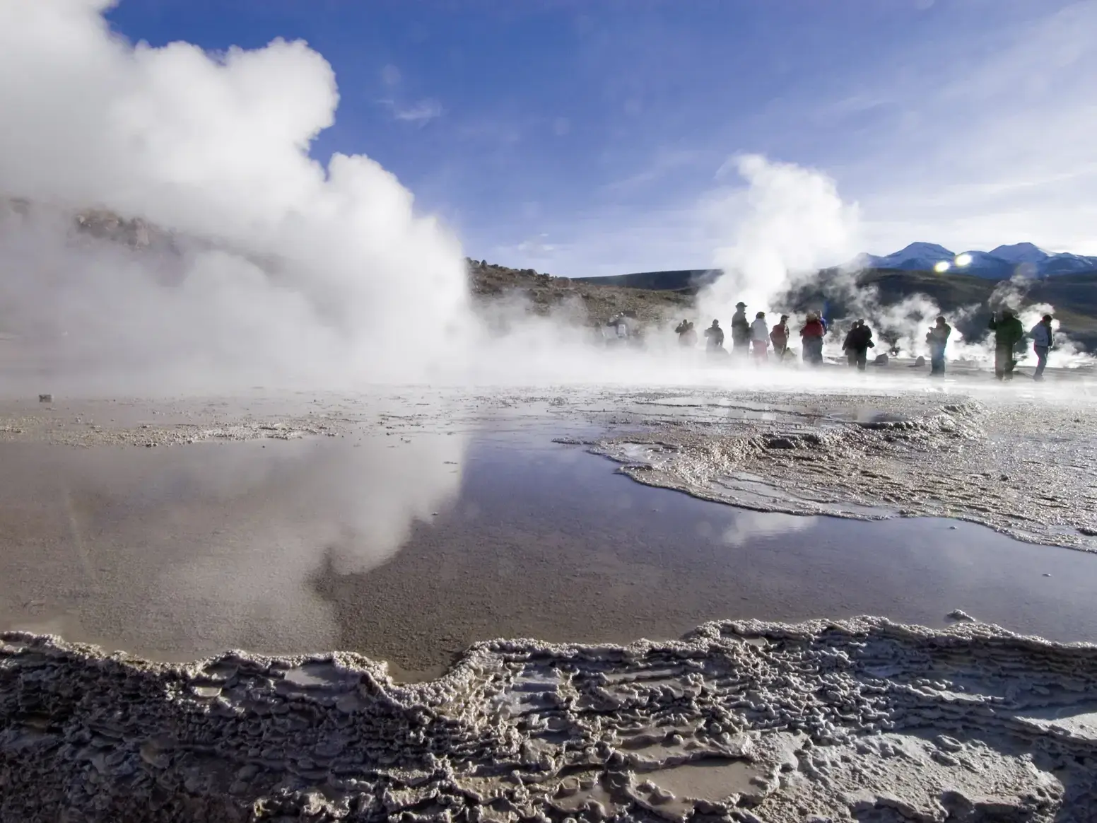 Eine Hauser Reisegruppe beobachtet bei Sonnenaufgang die dampfenden Fontänen der Tatio-Geysire in der Atacama-Wüste Chiles.