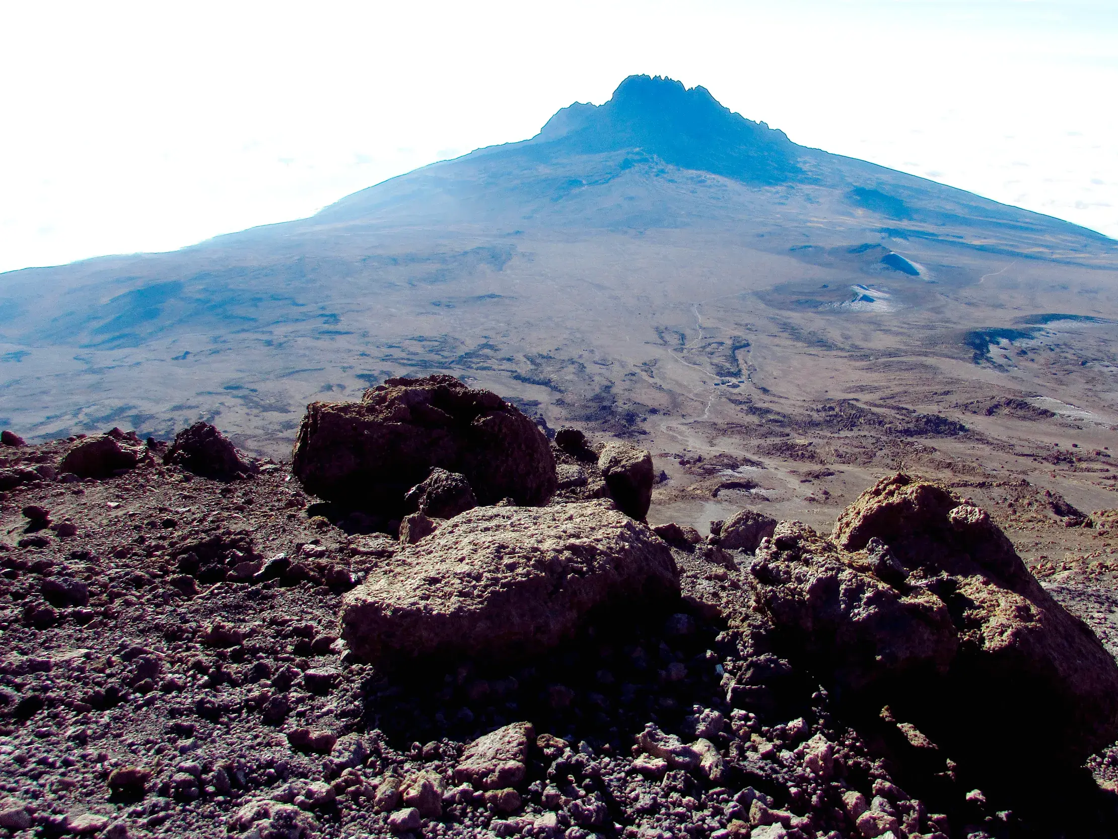 Steinige Vulkanlandschaft auf dem Kibo-Sattel mit weitem Blick auf den Uhuru Peak des Kilimanjaro in Tansania.