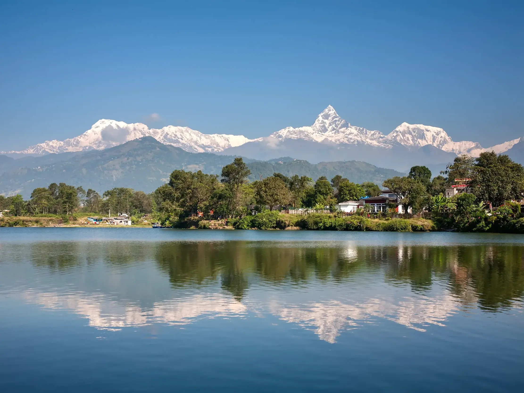 Malerische Spiegelung des Annapurna-Massivs und des markanten Machapuchare im ruhigen Phewa-See bei Pokhara, Nepal.