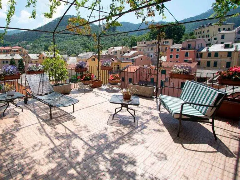 Sonnige Dachterrasse des Hotel Nazionale in Levanto mit Liegestühlen unter Weinreben und Blick auf die farbenfrohen Häuser.