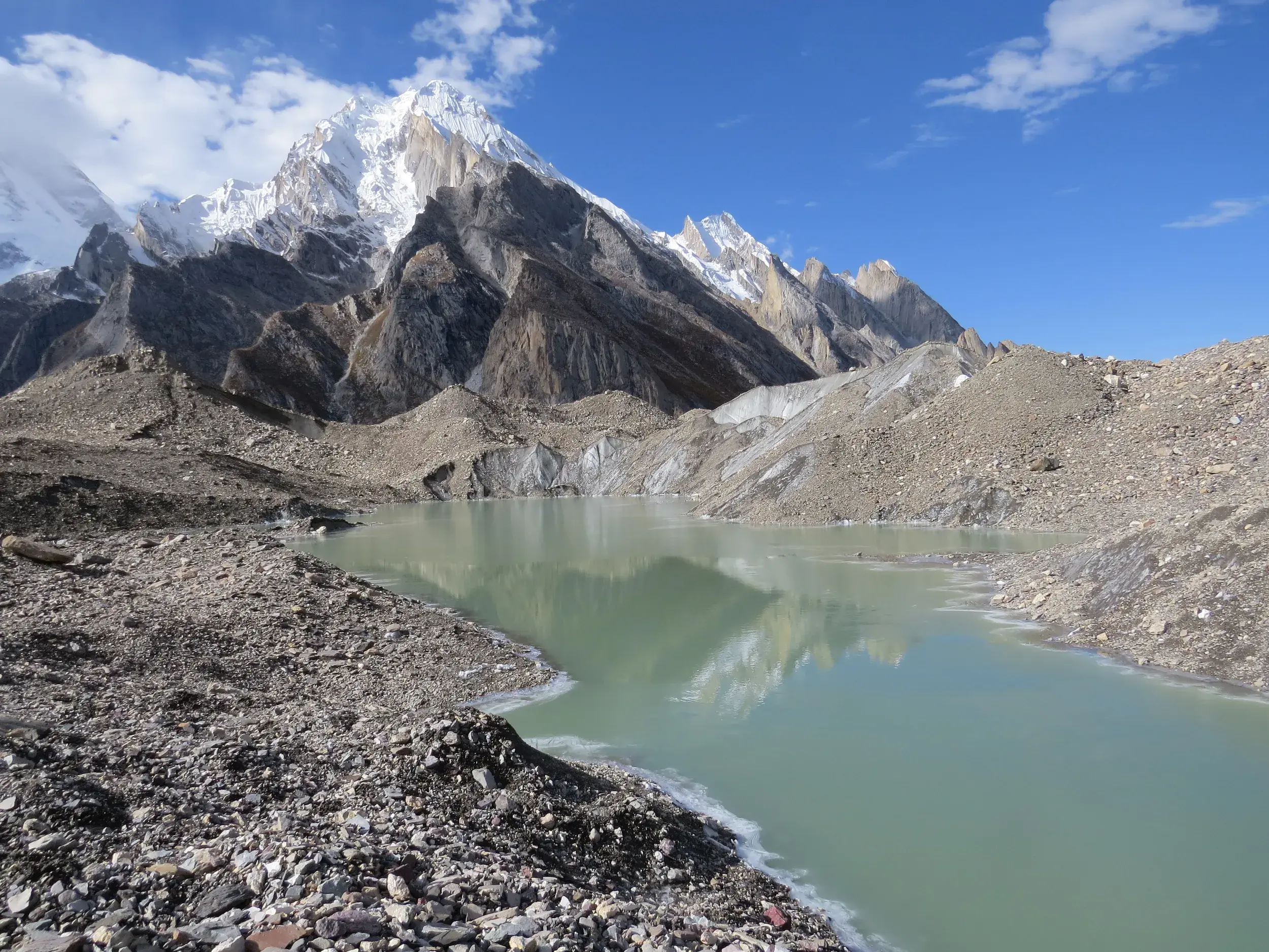 Gletschersee am Gondogoro-Gletscher, in dem sich der markante, schneebedeckte Gipfel des Laila Peak in Pakistan spiegelt.