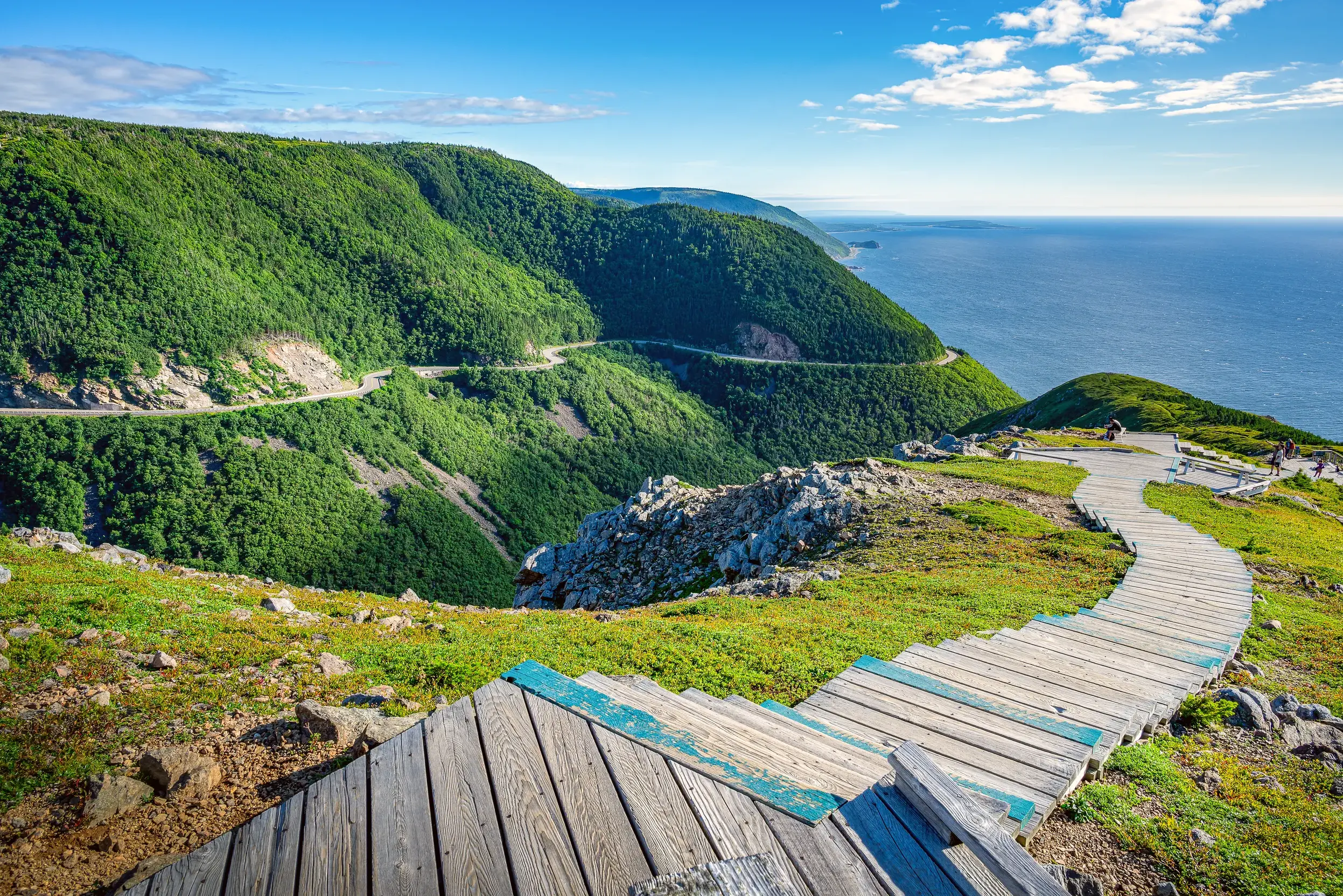 Ein Holzsteg führt zu einem Aussichtspunkt am Cabot Trail mit Panoramablick auf die Küste des Cape-Breton-Highlands-Nationalparks.