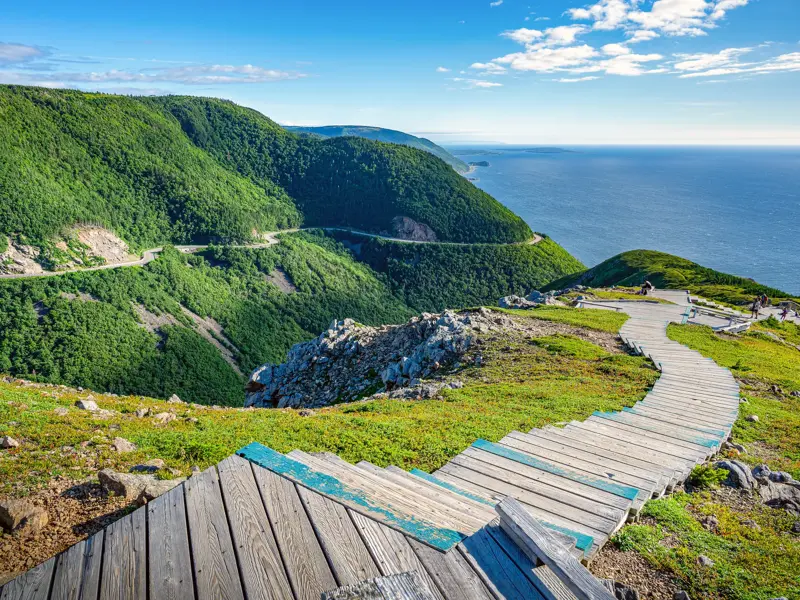 Ein Holzsteg führt zu einem Aussichtspunkt am Cabot Trail mit Panoramablick auf die Küste des Cape-Breton-Highlands-Nationalparks.