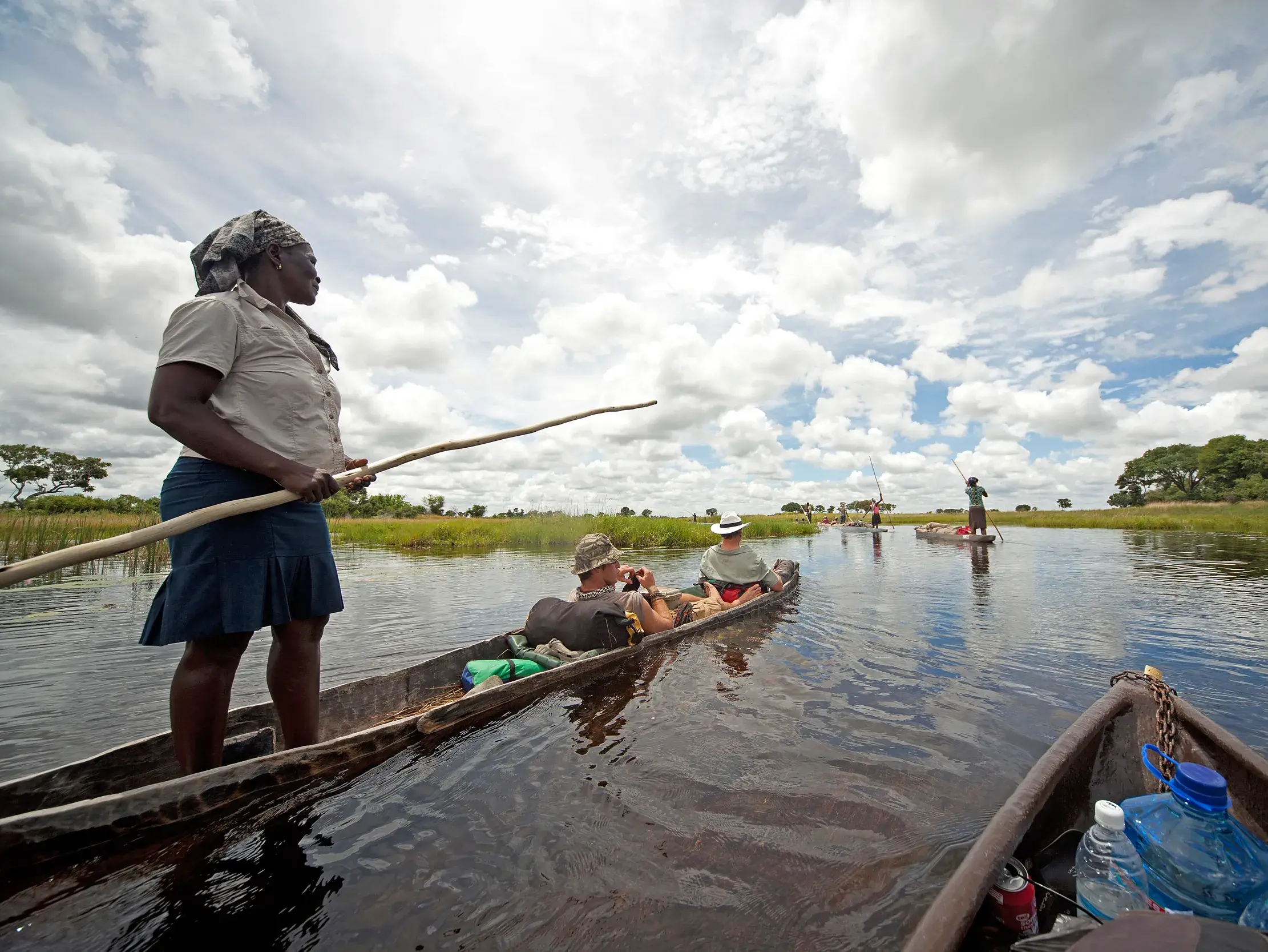 Einheimische Führerin stakt ein traditionelles Mokoro-Kanu mit Gästen einer Kleingruppenreise durch das Okavangodelta in Botswana.