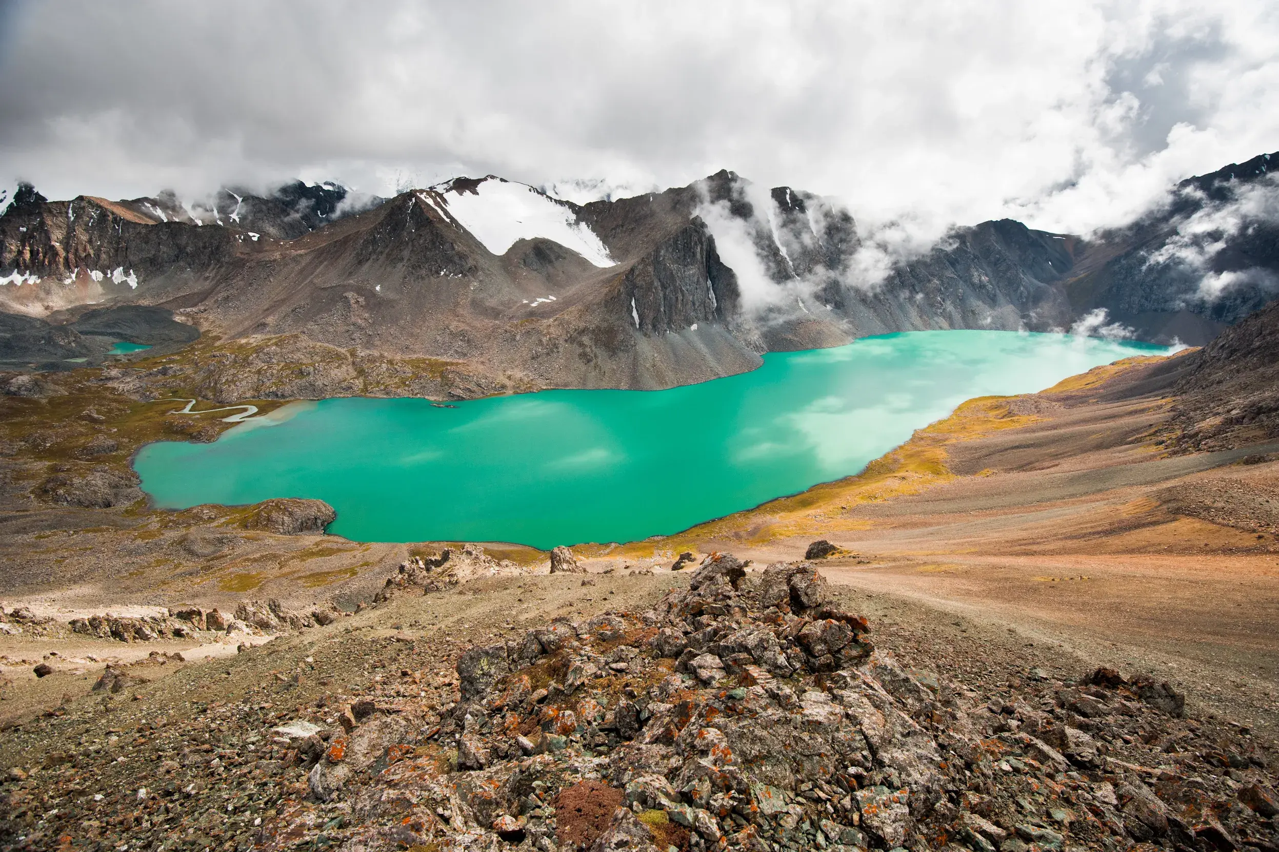 Panoramablick vom Trekkingpfad auf den türkisen Alaköl See im Terskej-Alatau-Gebirge in Kirgistan.