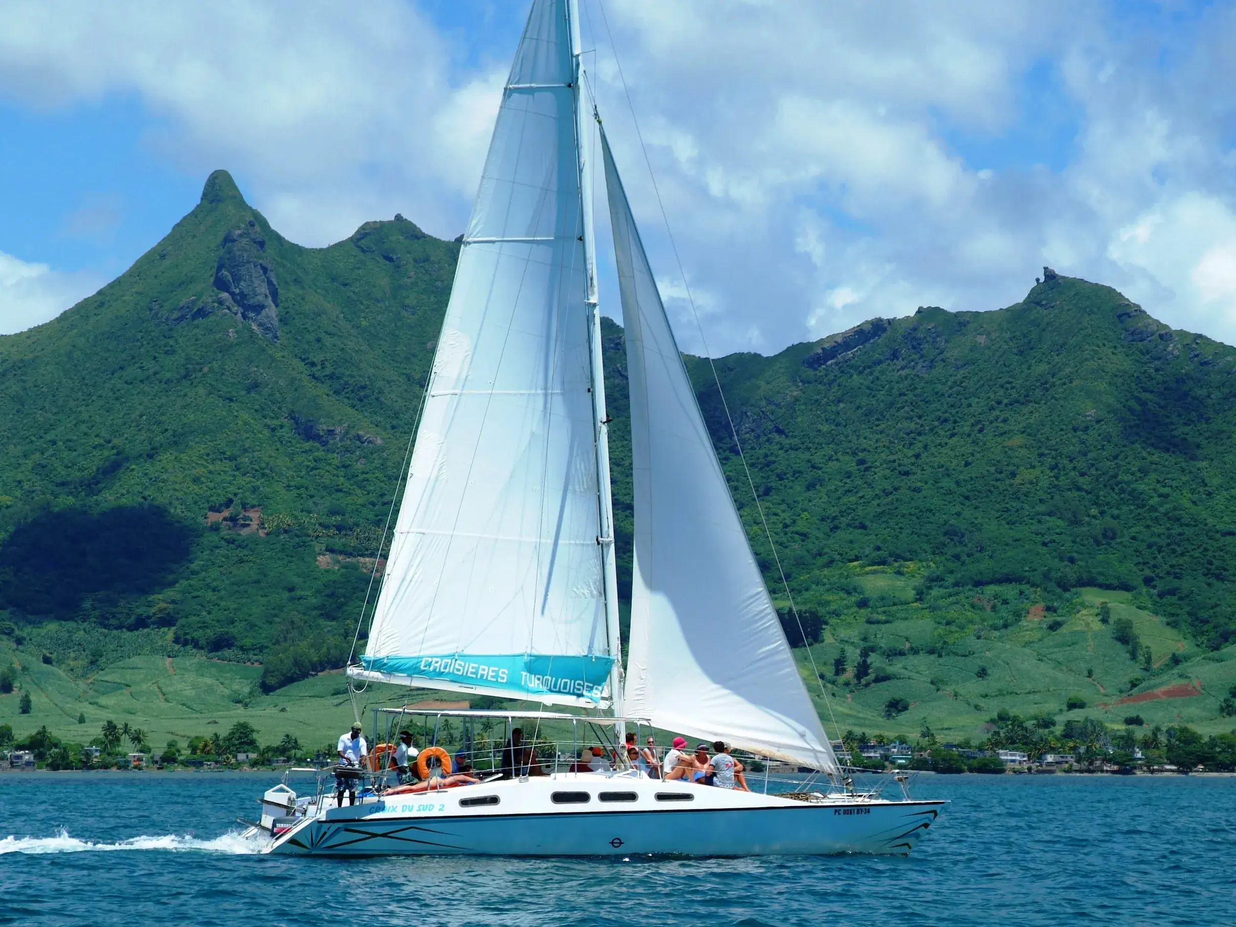 Reisegruppe auf einem Katamaran-Ausflug im Indischen Ozean vor der tropischen Bergkulisse von Mauritius.