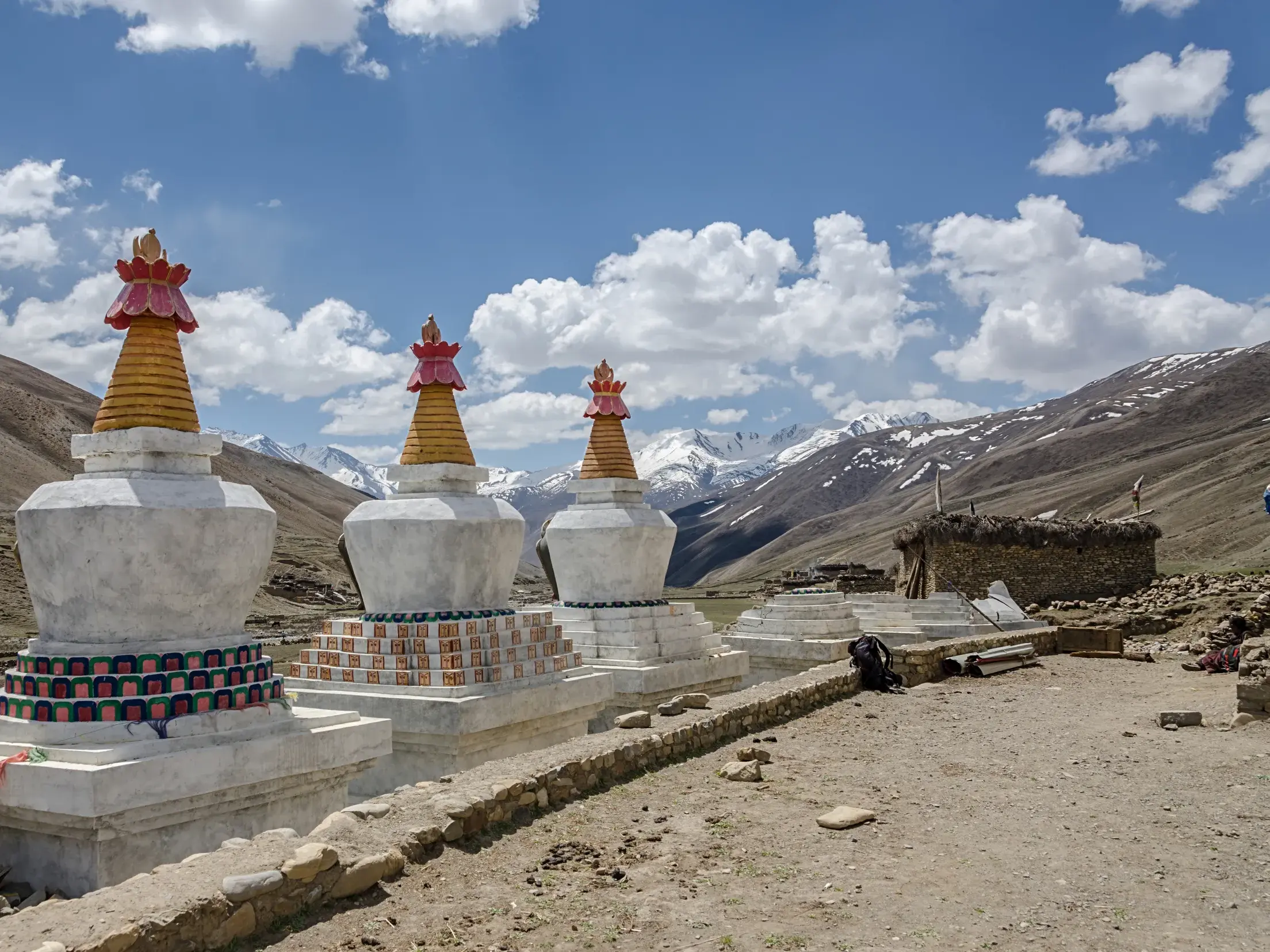 Eine Reihe weißer buddhistischer Stupas mit bunten Spitzen vor der kargen Berglandschaft der Dolpo-Region im nepalesischen Himalaya.