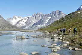 Eine Hauser Reisegruppe beim Trekking am Tasiilaq-Kuua in Ostgrönland mit Blick auf die schneebedeckten Pikkelhuen-Berge.