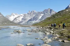 Eine Hauser Reisegruppe beim Trekking am Tasiilaq-Kuua in Ostgrönland mit Blick auf die schneebedeckten Pikkelhuen-Berge.