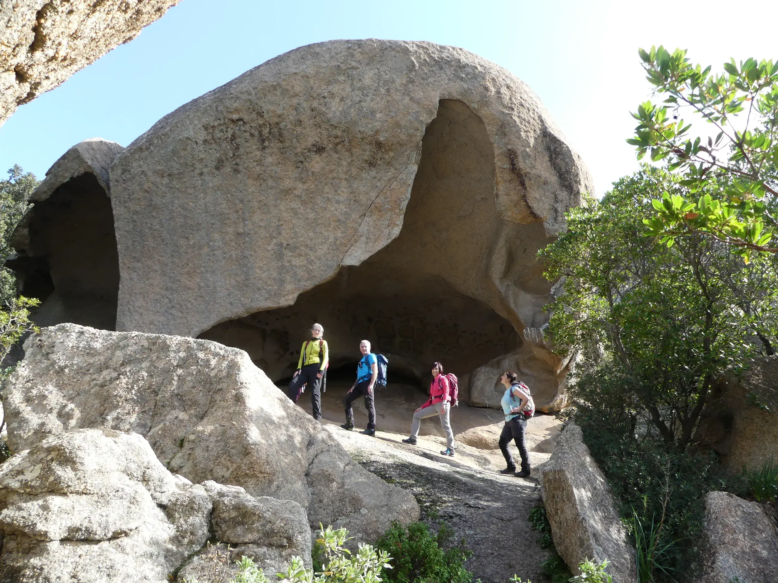 Eine kleine Reisegruppe erkundet die bizarren, gigantischen Granitaushöhlungen während einer Wanderung bei Onifai auf Sardinien.