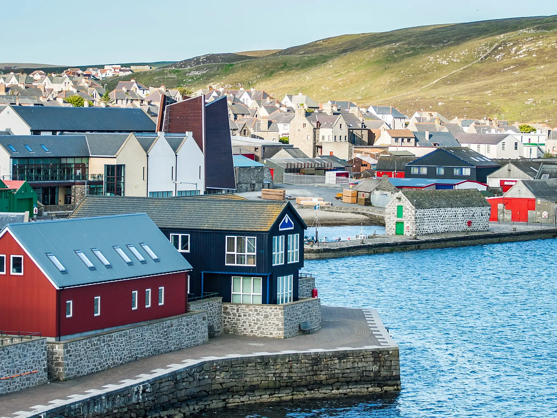 Farbige Holzhäuser und historische Steingebäude am Kai des Hafens von Lerwick auf den Shetland-Inseln in Schottland.