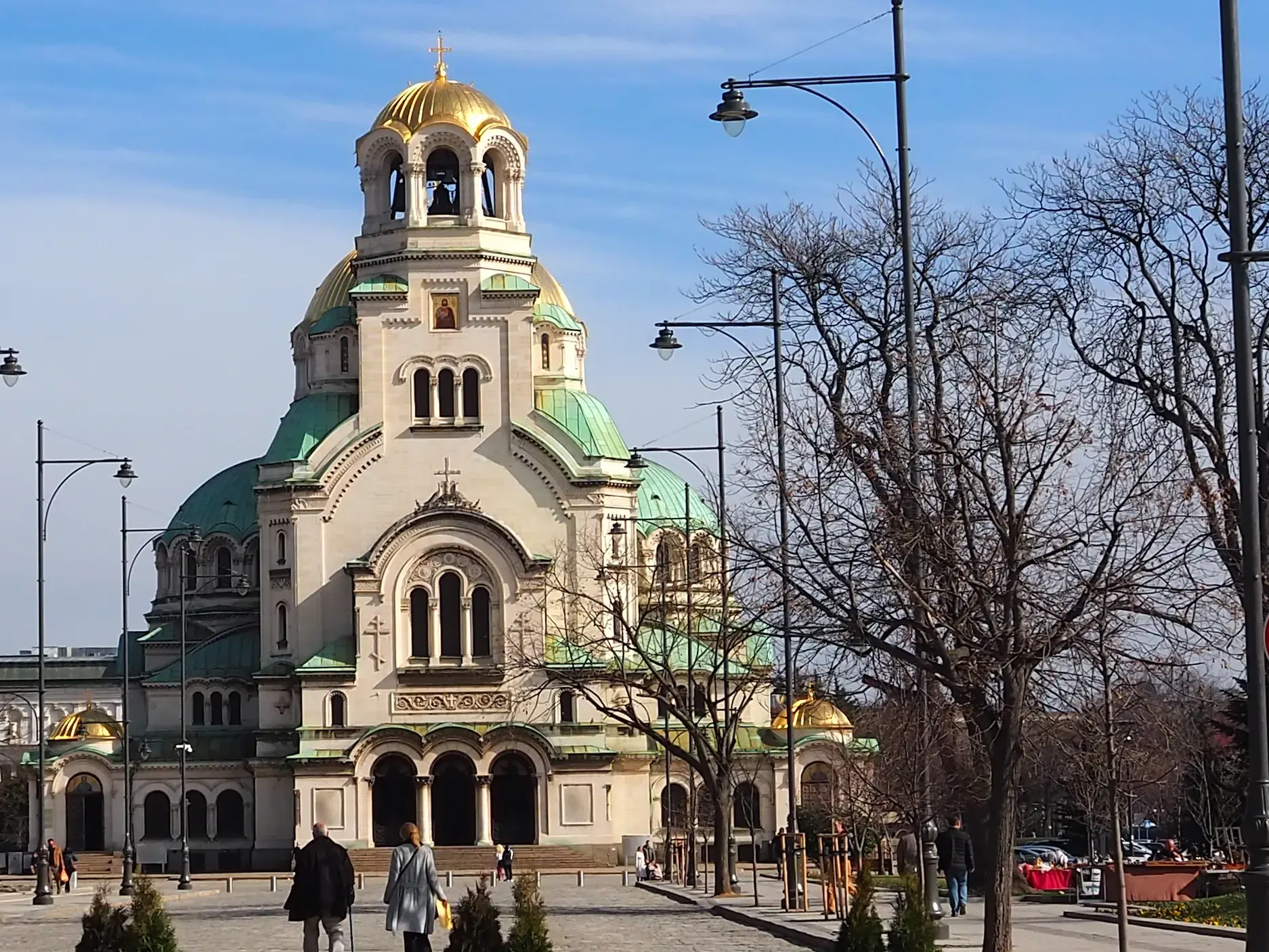Passanten spazieren an einem sonnigen Tag vor der prächtigen Alexander-Newski-Kathedrale mit goldenen Kuppeln in Sofia.