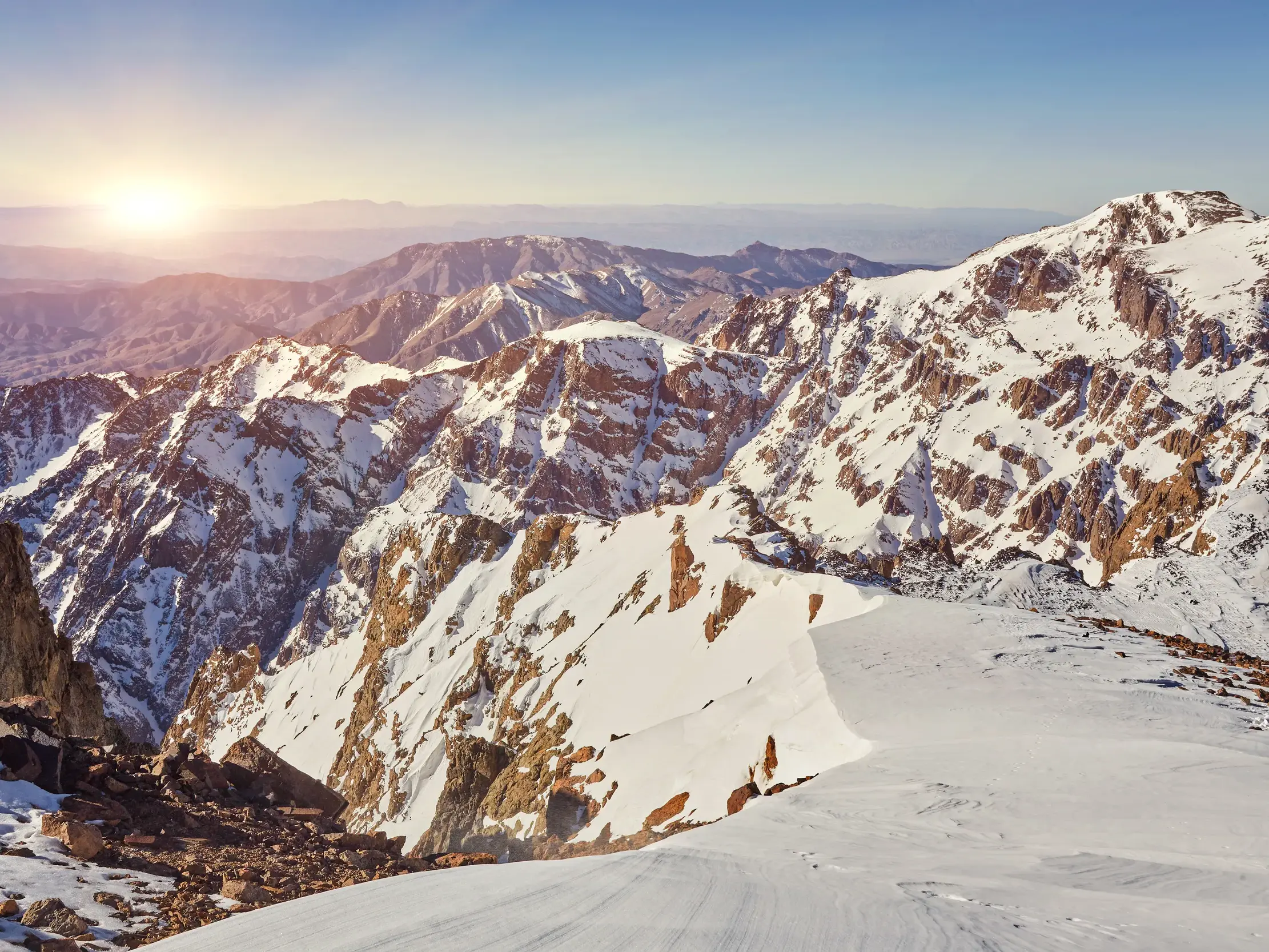 Panoramablick vom Gipfel des Toubkal auf die verschneiten Berge des Hohen Atlas in Marokko bei Sonnenaufgang.