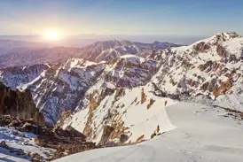 Panoramablick vom Gipfel des Toubkal auf die verschneiten Berge des Hohen Atlas in Marokko bei Sonnenaufgang.