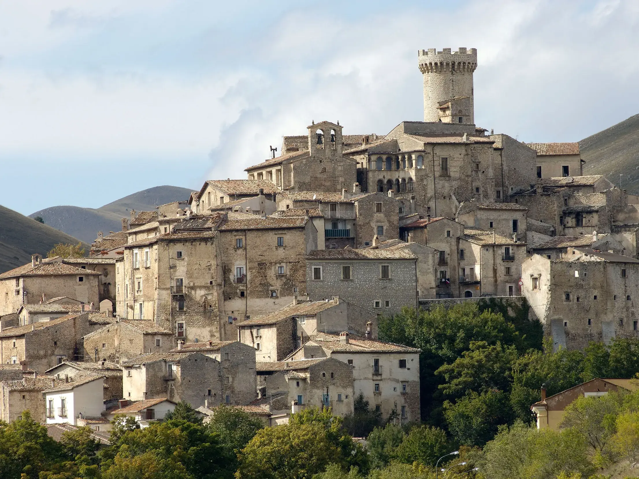 Die historischen Steinhäuser des Bergdorfs Castel del Monte schmiegen sich an einen grünen Berghang in den Abruzzen.