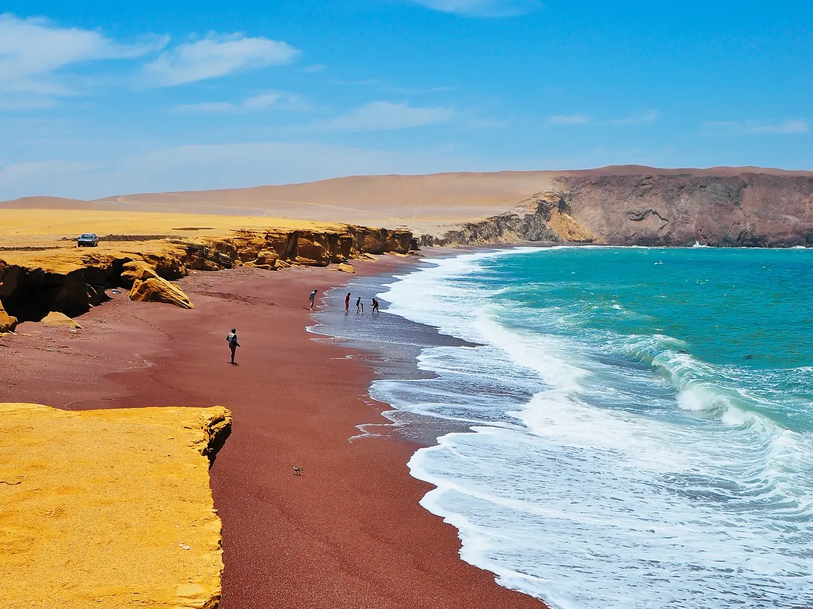 Leuchtend gelbe Klippen treffen auf den roten Sandstrand Playa Roja im Paracas-Nationalpark an der Küste von Peru.