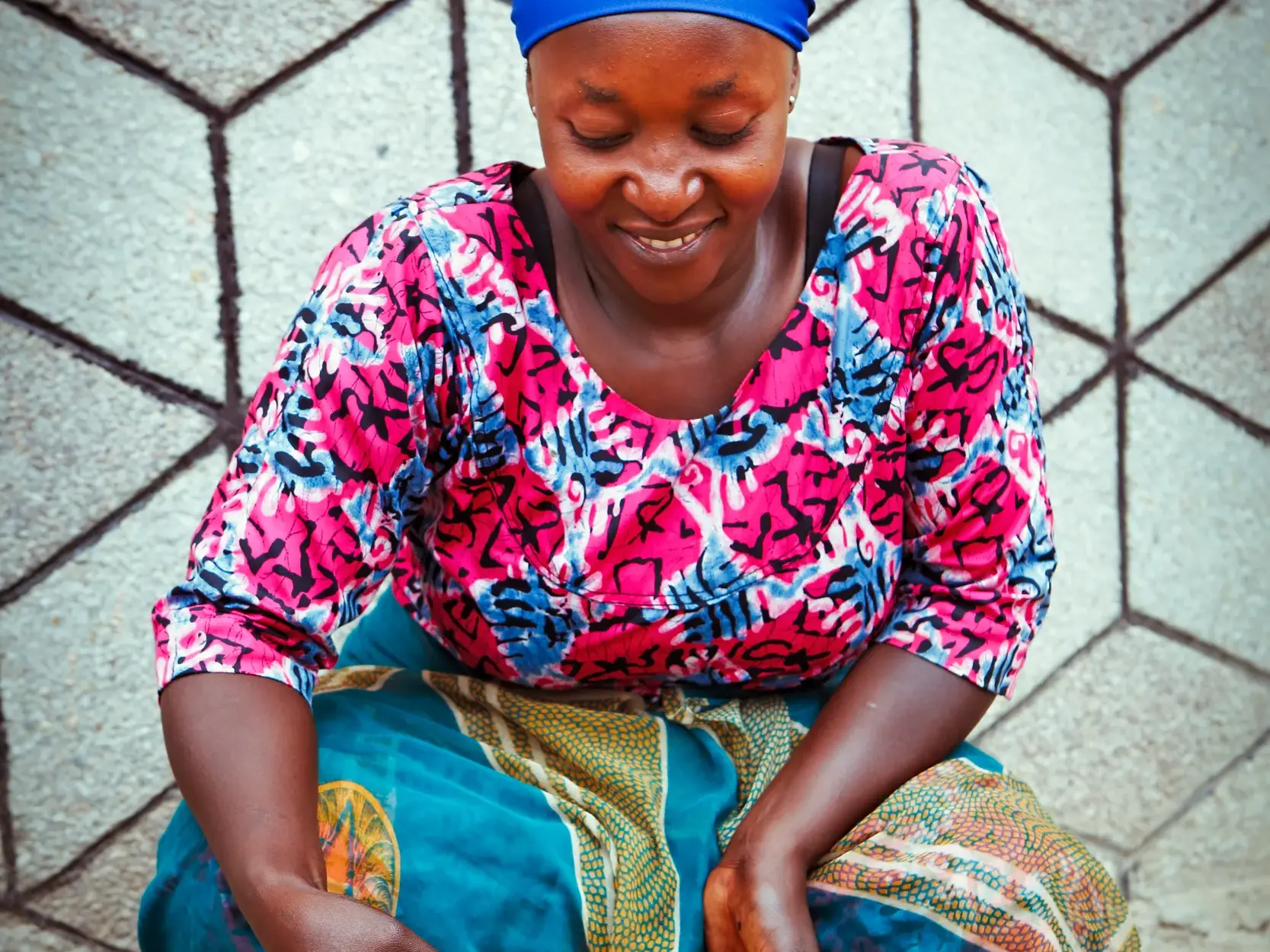 Eine lächelnde Frau aus Uganda in farbenfroher Kleidung während einer kulturellen Begegnung auf einer Studienreise.