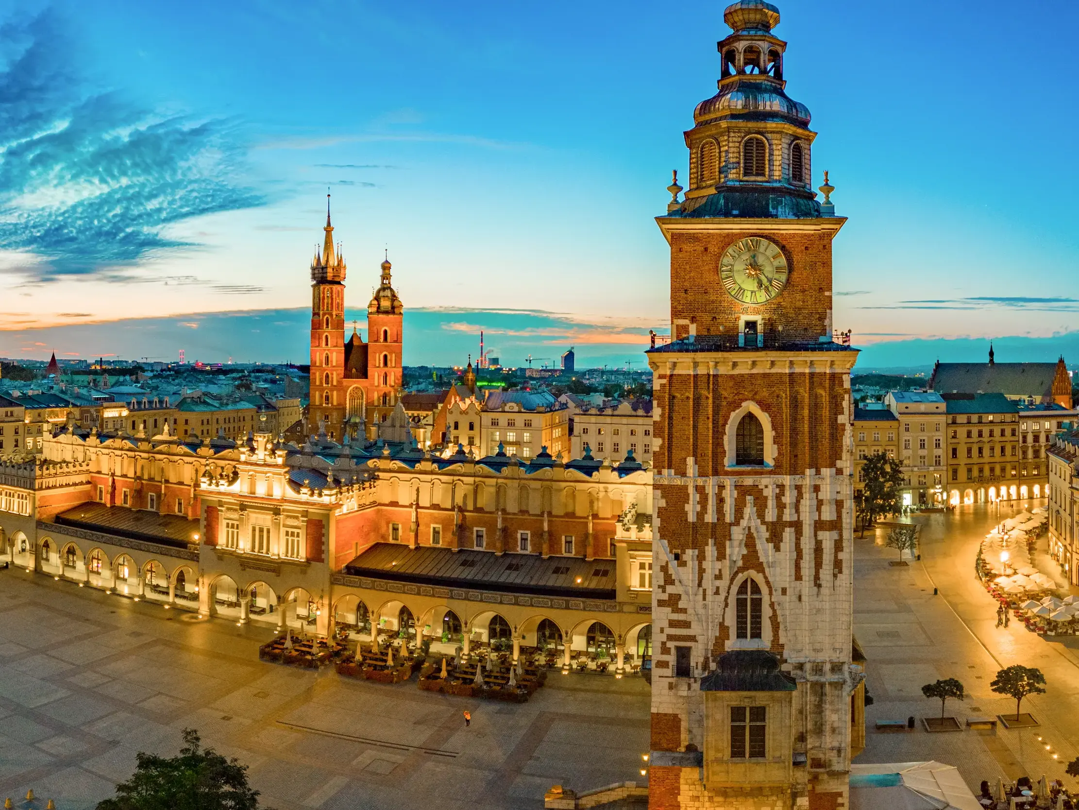 Abendlicher Panoramablick auf die historische Altstadt von Krakau mit den beleuchteten Tuchhallen und der Marienkirche.