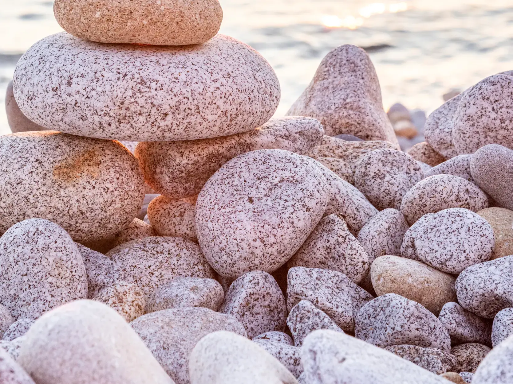 Detailaufnahme von glatten Kieselsteinen aus Granit am Strand von Pomonte auf der Insel Elba bei Sonnenuntergang.