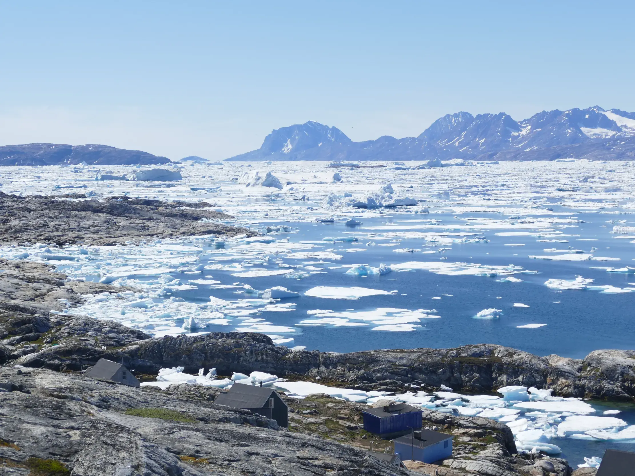 Blick von der Inuit-Siedlung Tiniteqilaaq über den eisgefüllten Sermilik-Fjord auf eine Bergkette in Ostgrönland.