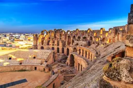 Blick von den Rängen auf die sandige Arena des imposanten römischen Amphitheaters in El-Djem bei strahlend blauem Himmel.