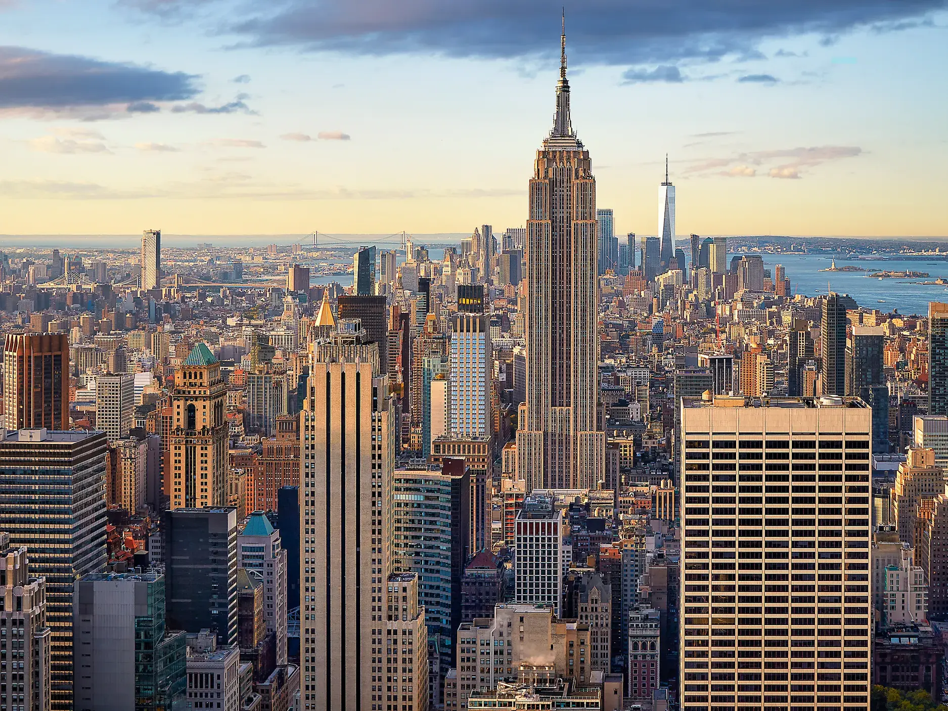 Blick auf Manhattan mit dem Empire State Building und dem One World Trade Center im warmen Nachmittagslicht