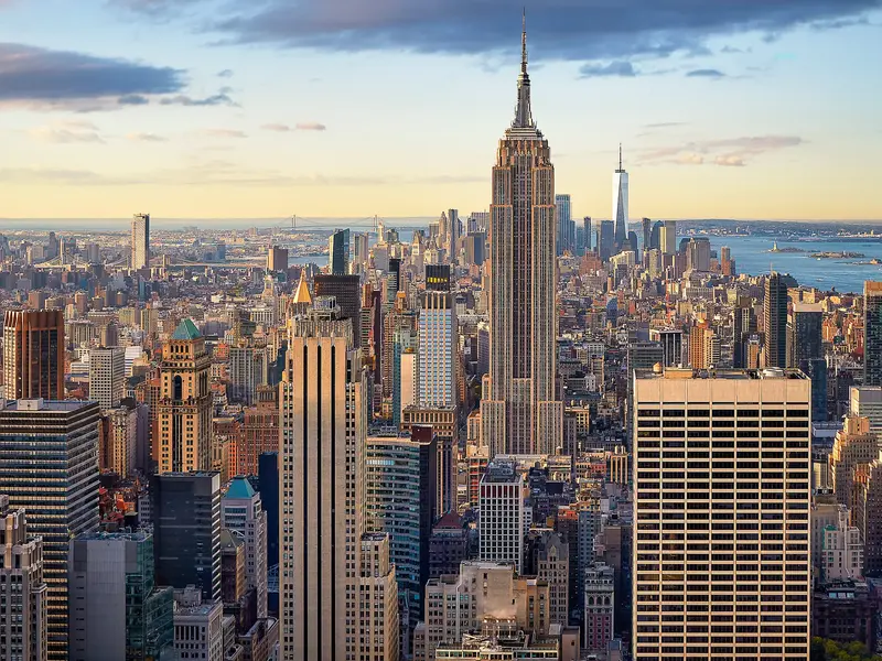 Blick auf Manhattan mit dem Empire State Building und dem One World Trade Center im warmen Nachmittagslicht