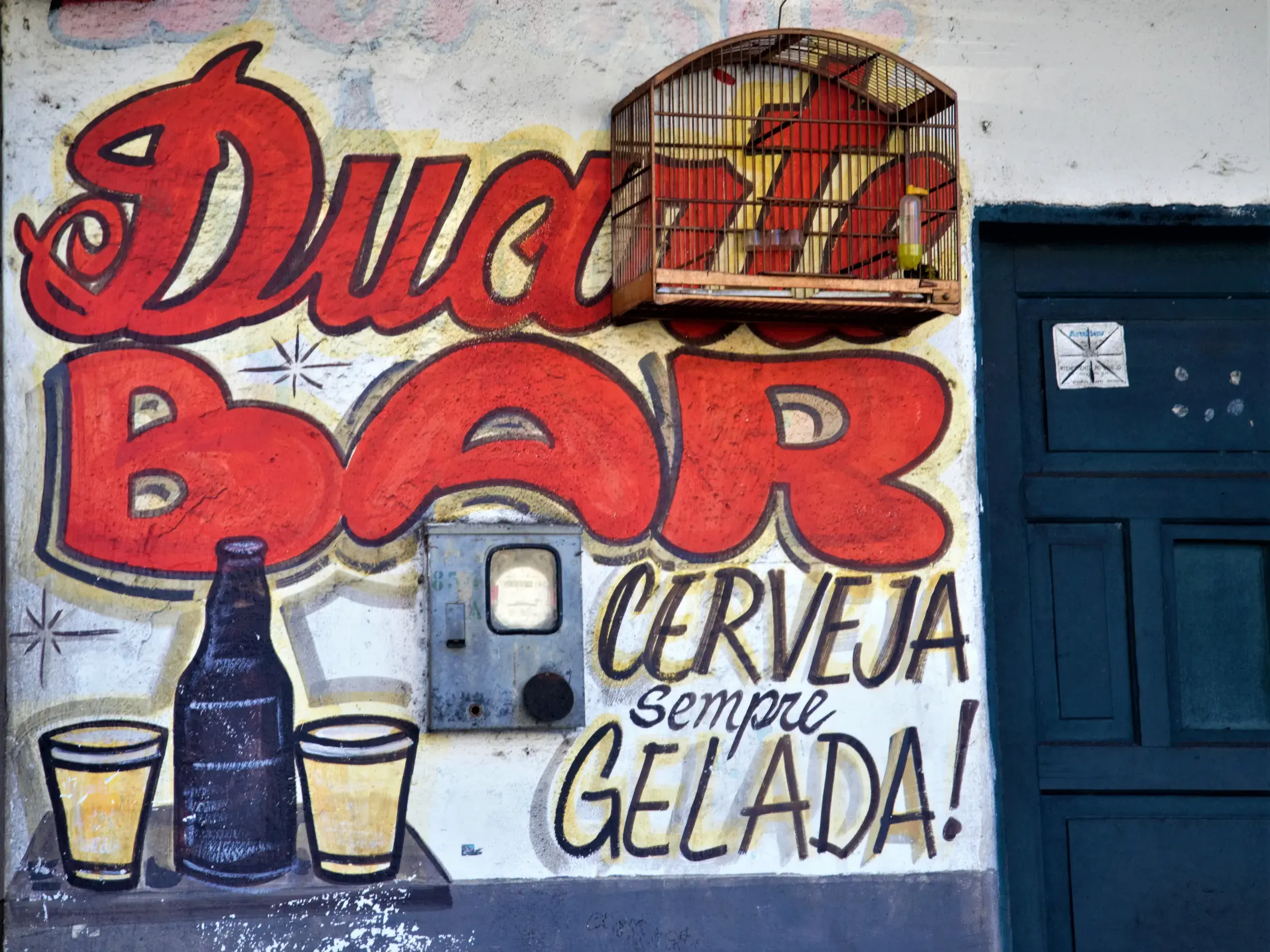 Farbenfrohes Wandgemälde für die "Duda Bar" an einer Hauswand in Brasilien mit der Aufschrift "Cerveja sempre gelada".