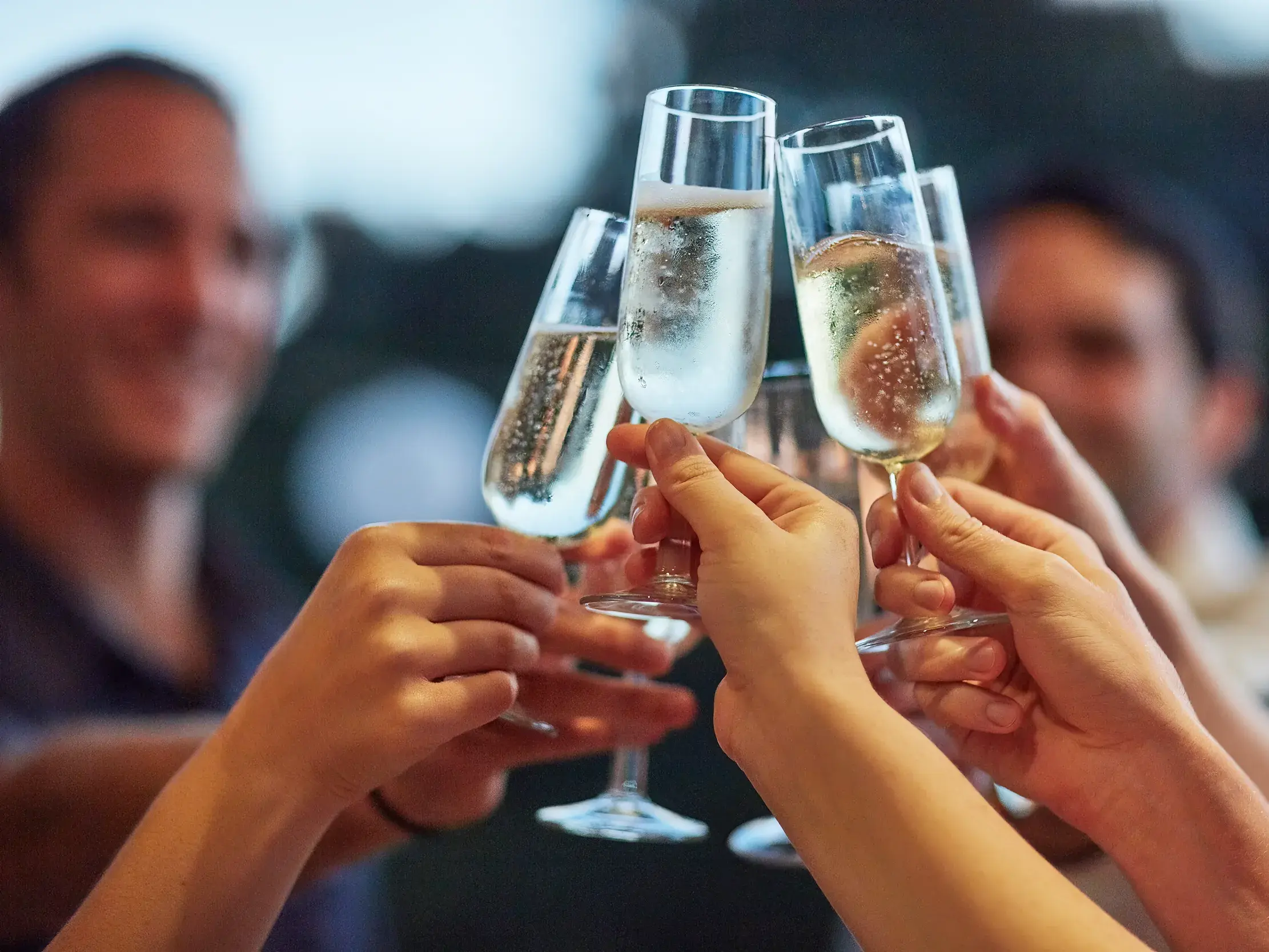 Eine Gruppe von Reisenden stößt an Silvester in Funchal auf Madeira feierlich mit gefüllten Sektgläsern an.