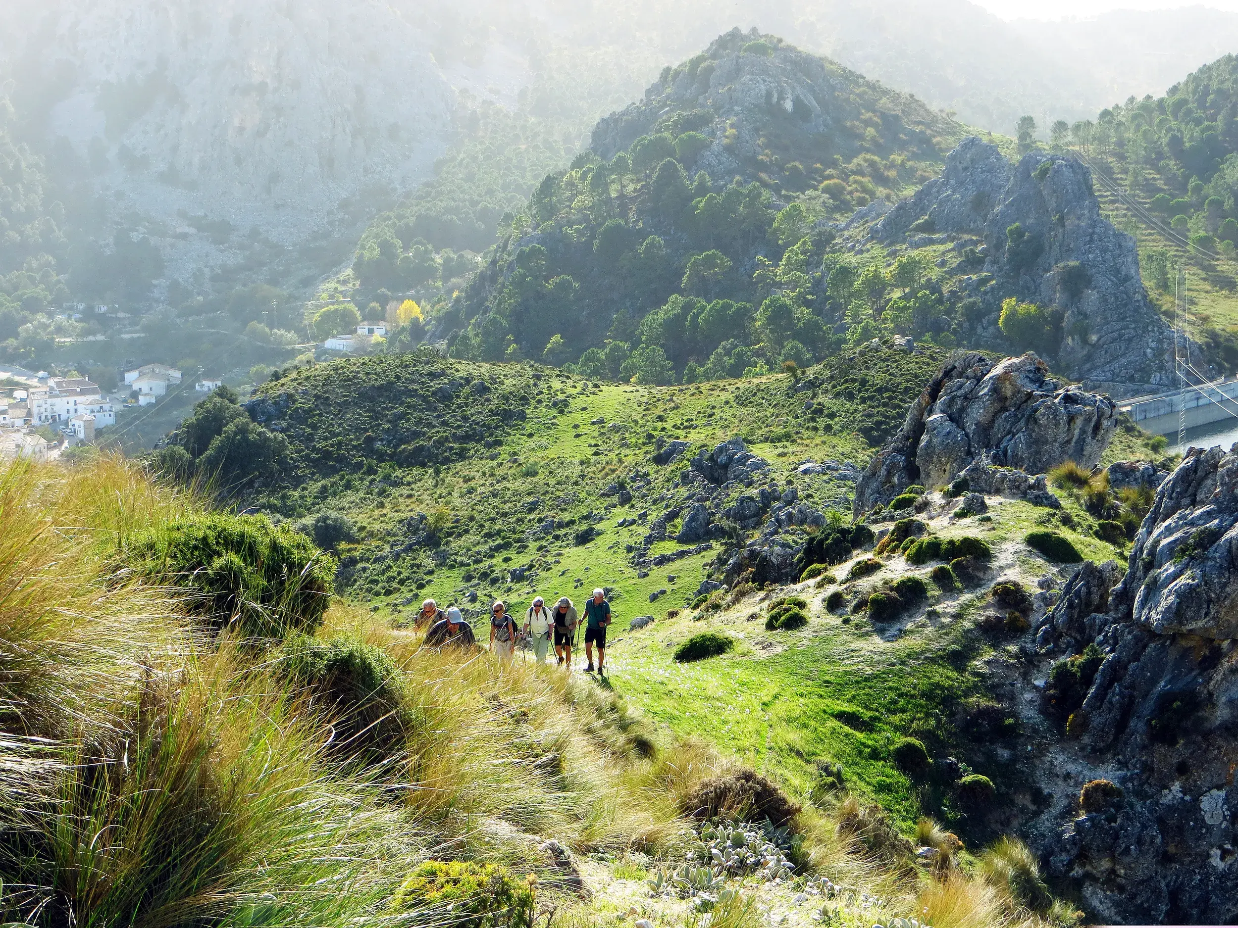 Eine Hauser-Wandergruppe auf einem Pfad in der Sierra de Grazalema mit Blick auf ein weißes Dorf in Andalusien.