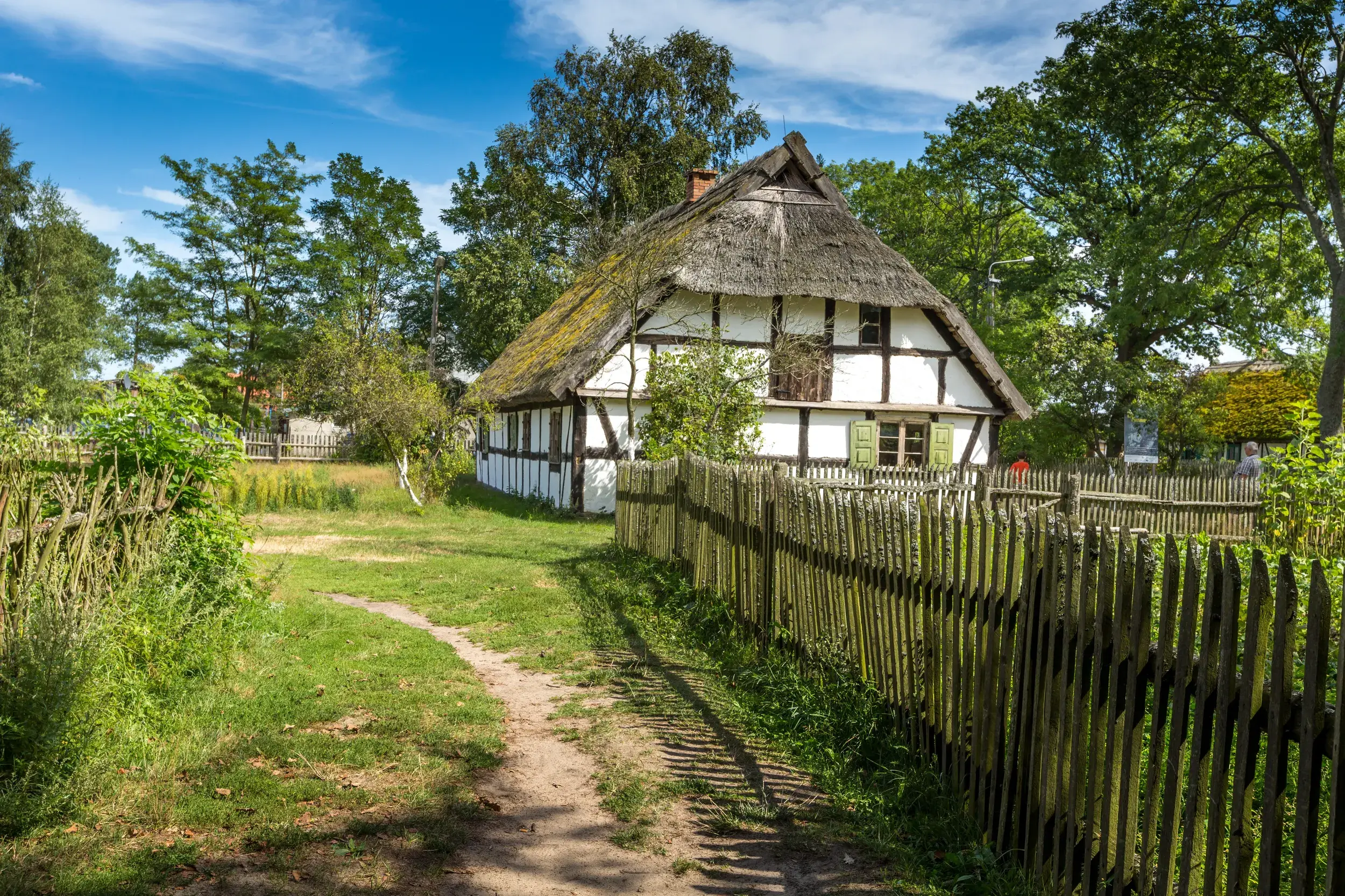 Traditioneller Bauernhof der Slowinzen im Freilichtmuseum Kluki, ein Fachwerkhaus mit Reetdach und rustikalem Holzzaun.