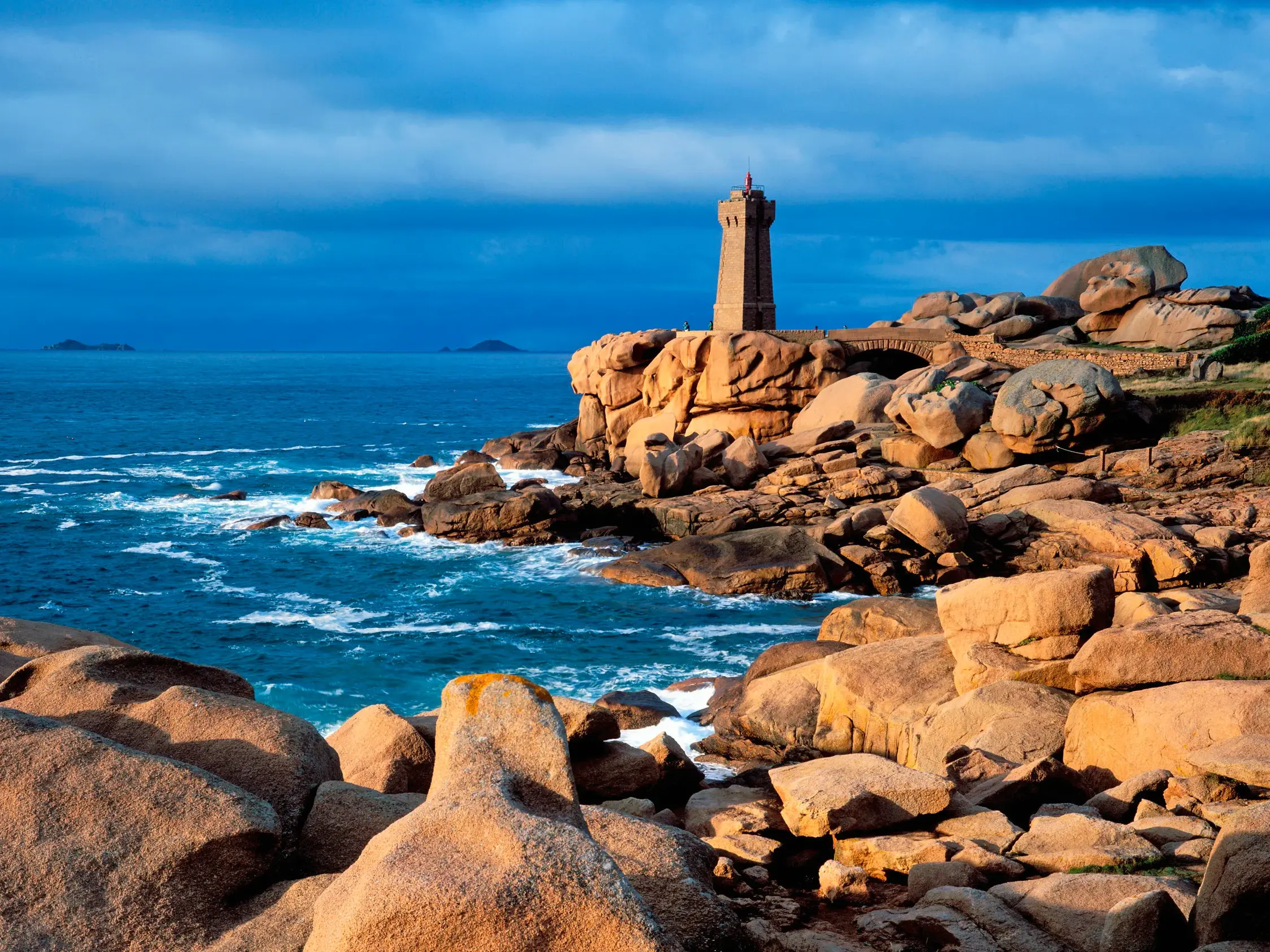 Der Leuchtturm von Ploumanach auf den charakteristischen Felsen der Rosengranitküste in der Bretagne bei aufgewühlter See.